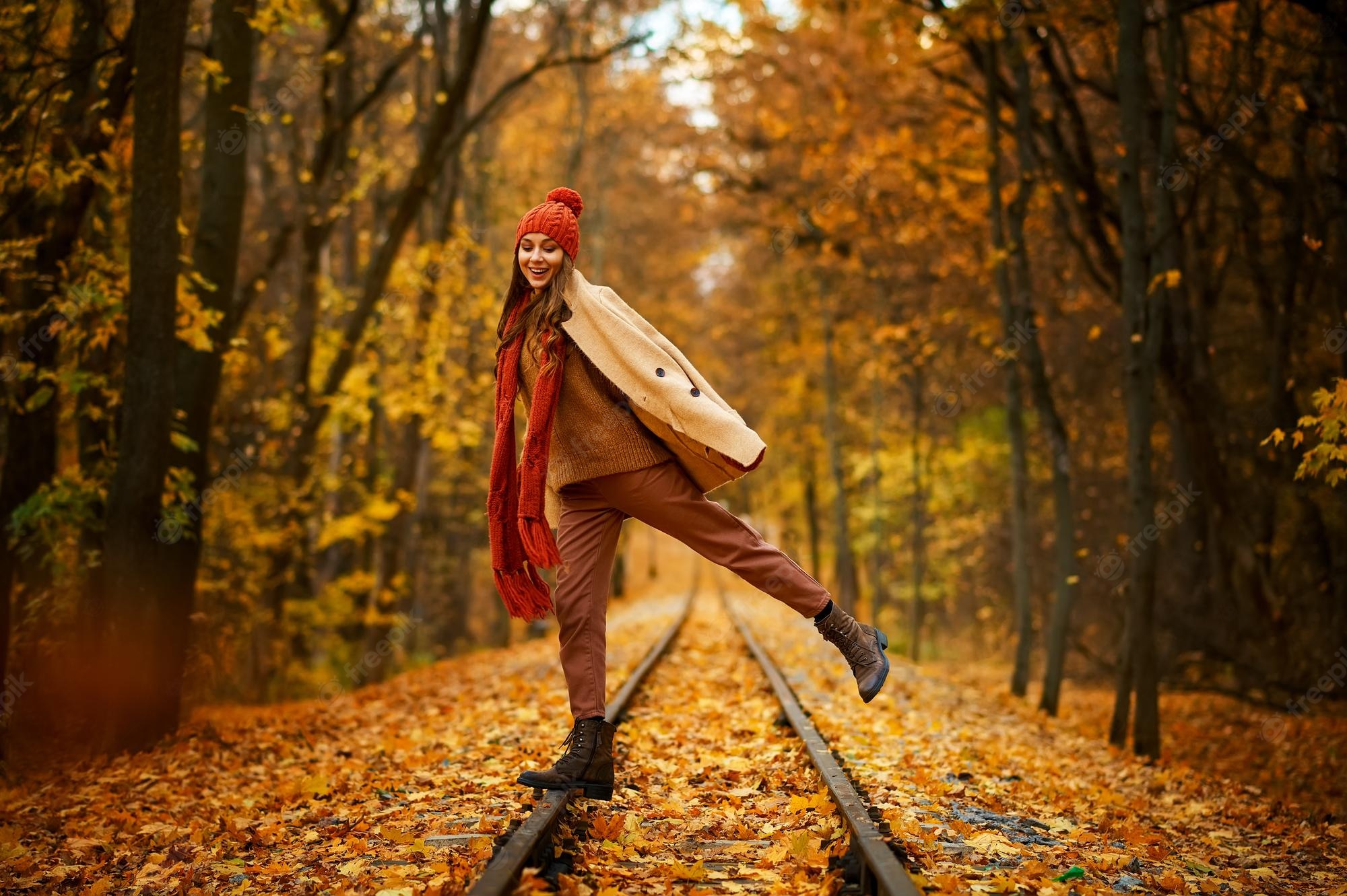 Premium Photo. Portrait of happy overjoyed woman in jump over railroad in autumn forest. excitement and fall weather
