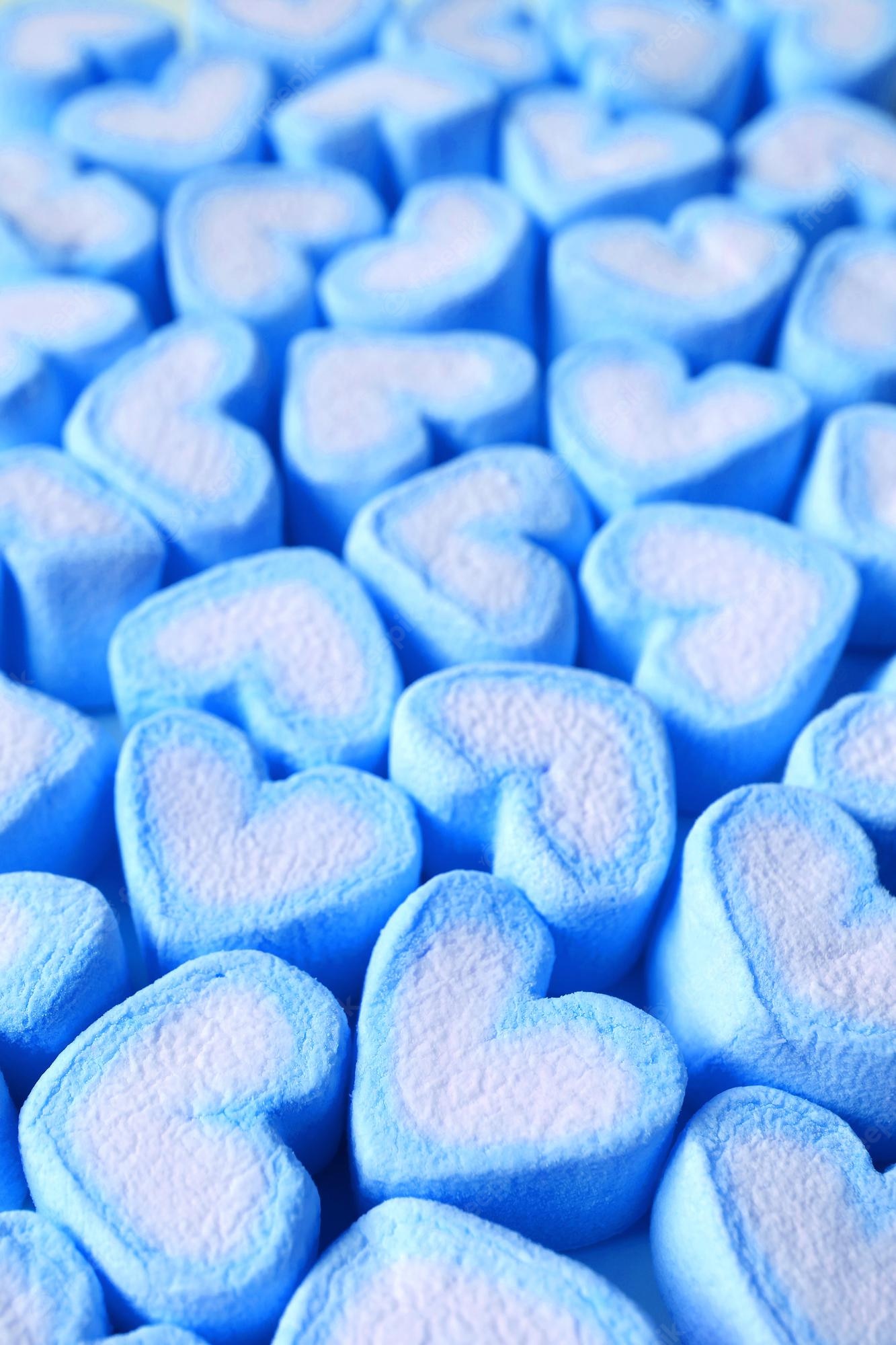 Premium Photo. Closeup heap of pastel ice blue and white heart shaped marshmallow candies for background or banner