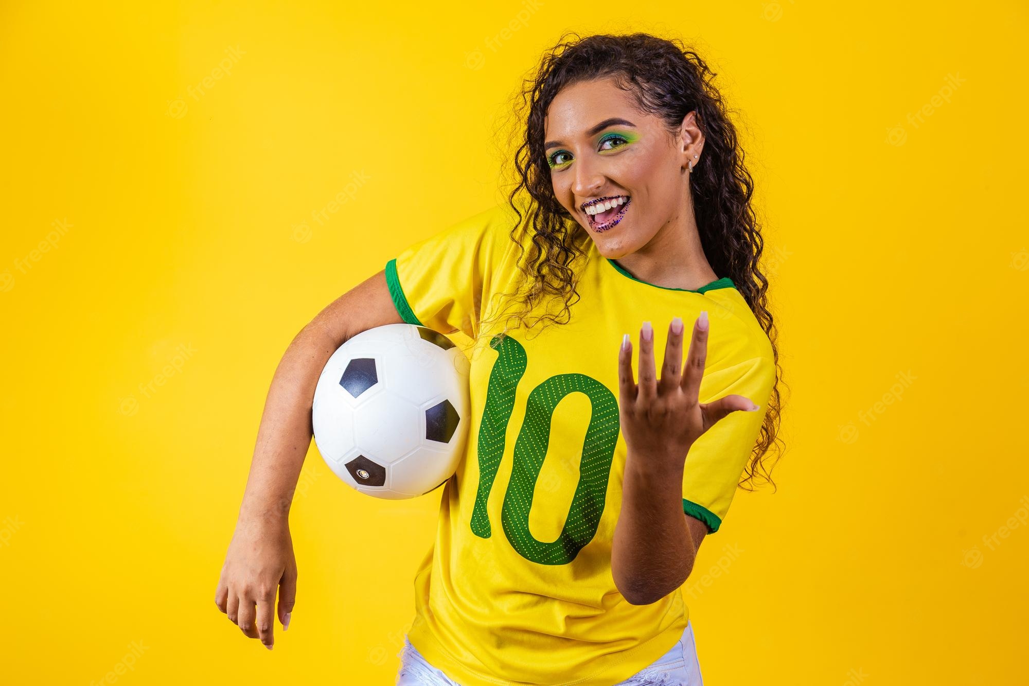 Premium Photo. Beautiful brazilian female supporter with a soccer ball on yellow background world cup 2022