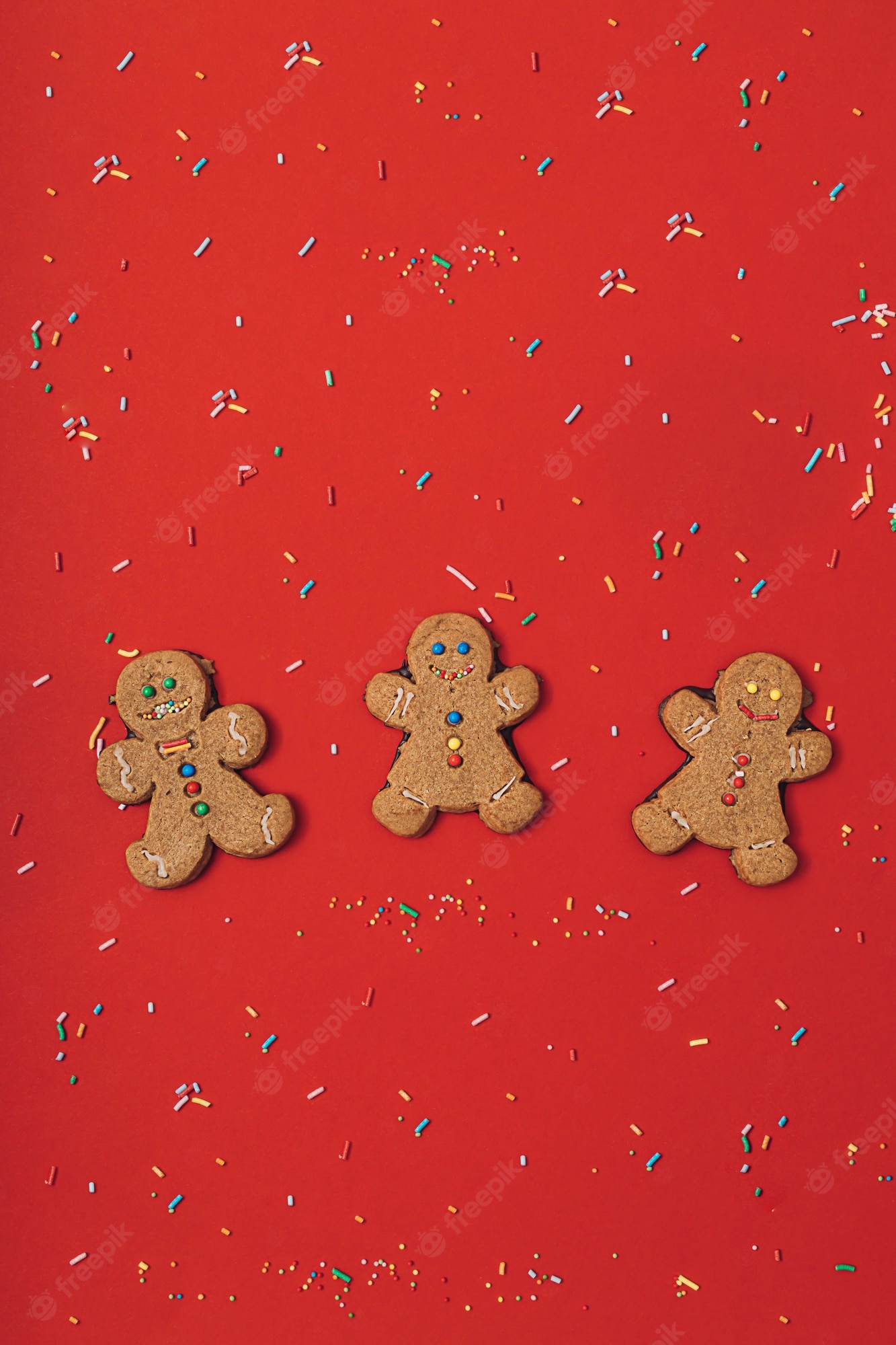 Premium Photo. Christmas gingerbread man cookie with icing, sugar sprinkles on a red table background. new year wallpaper flat lay. holiday pattern