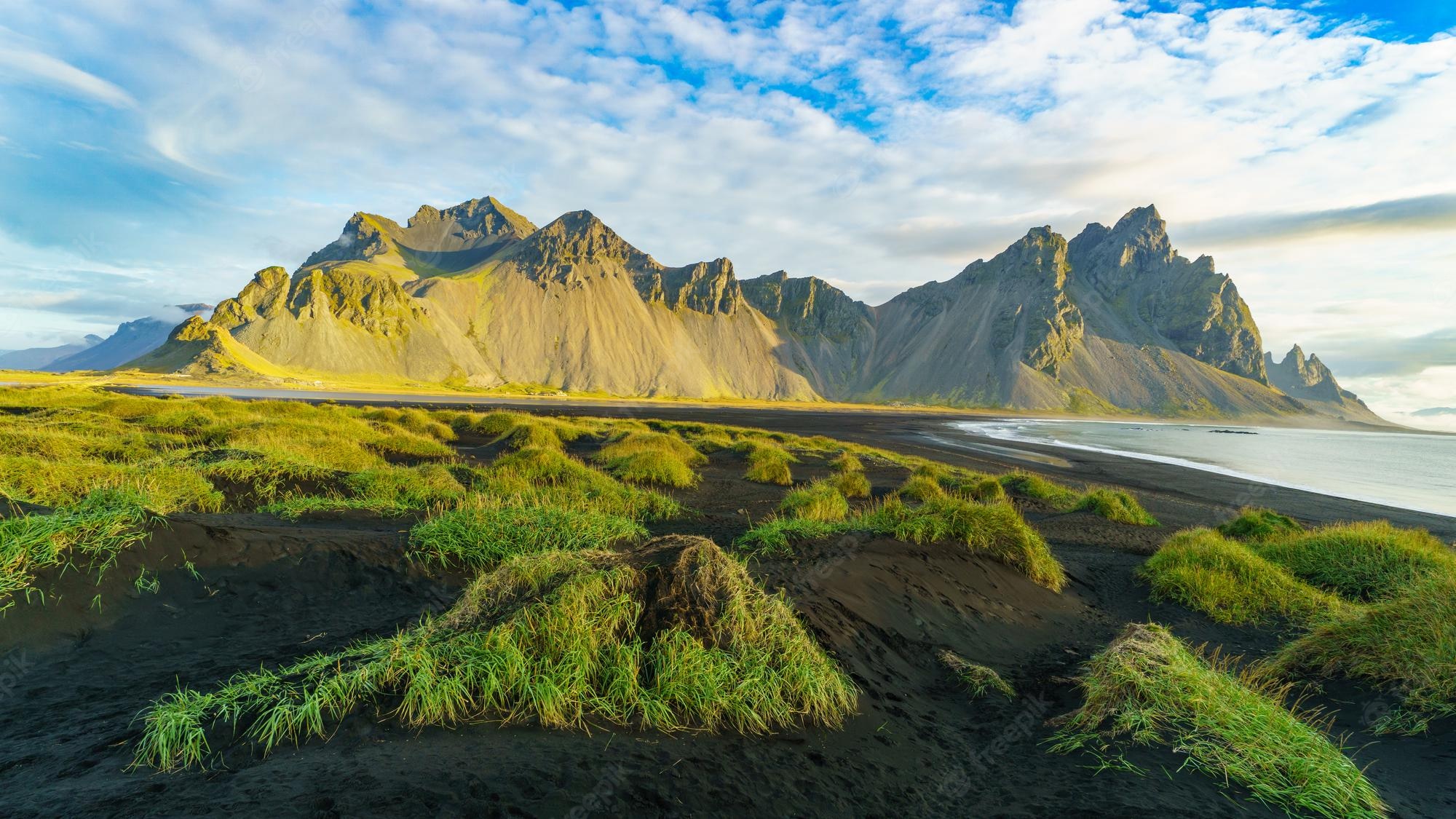 Premium Photo. Vesturhorn mountain in summer morning. stokksnes, iceland, northern europe, scandinavia. scenic beautiful nature landscape. vibrant sunrise mountains landscape wallpaper. popular tourist attraction