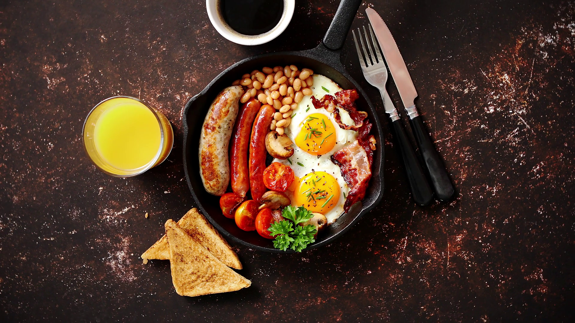 English Breakfast In Iron Cooking Pan With Fried Eggs, Sausages, Bacon, Beaked Beans, Toasts, Orange Juice And Black Coffee On Dark Rusty Background. Stock Video Footage 00:29 SBV 328269745