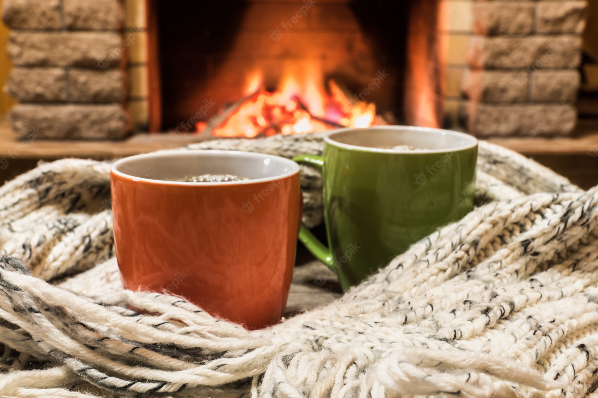 Premium Photo. Cozy scene near fireplace with cups of hot tea and cozy warm scarf