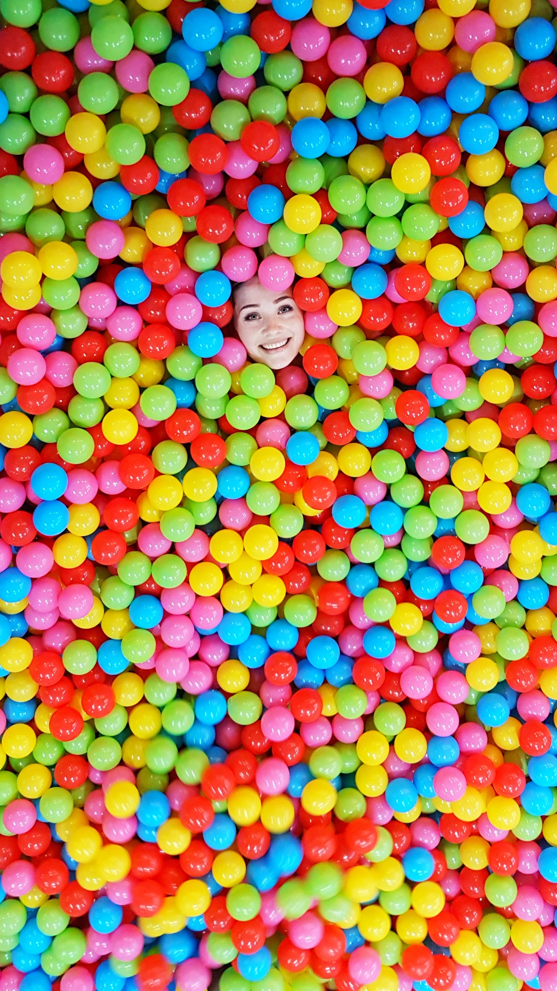 Woman Sitting in a Ball Pit Pool and Throwing Plastic Balls · Free