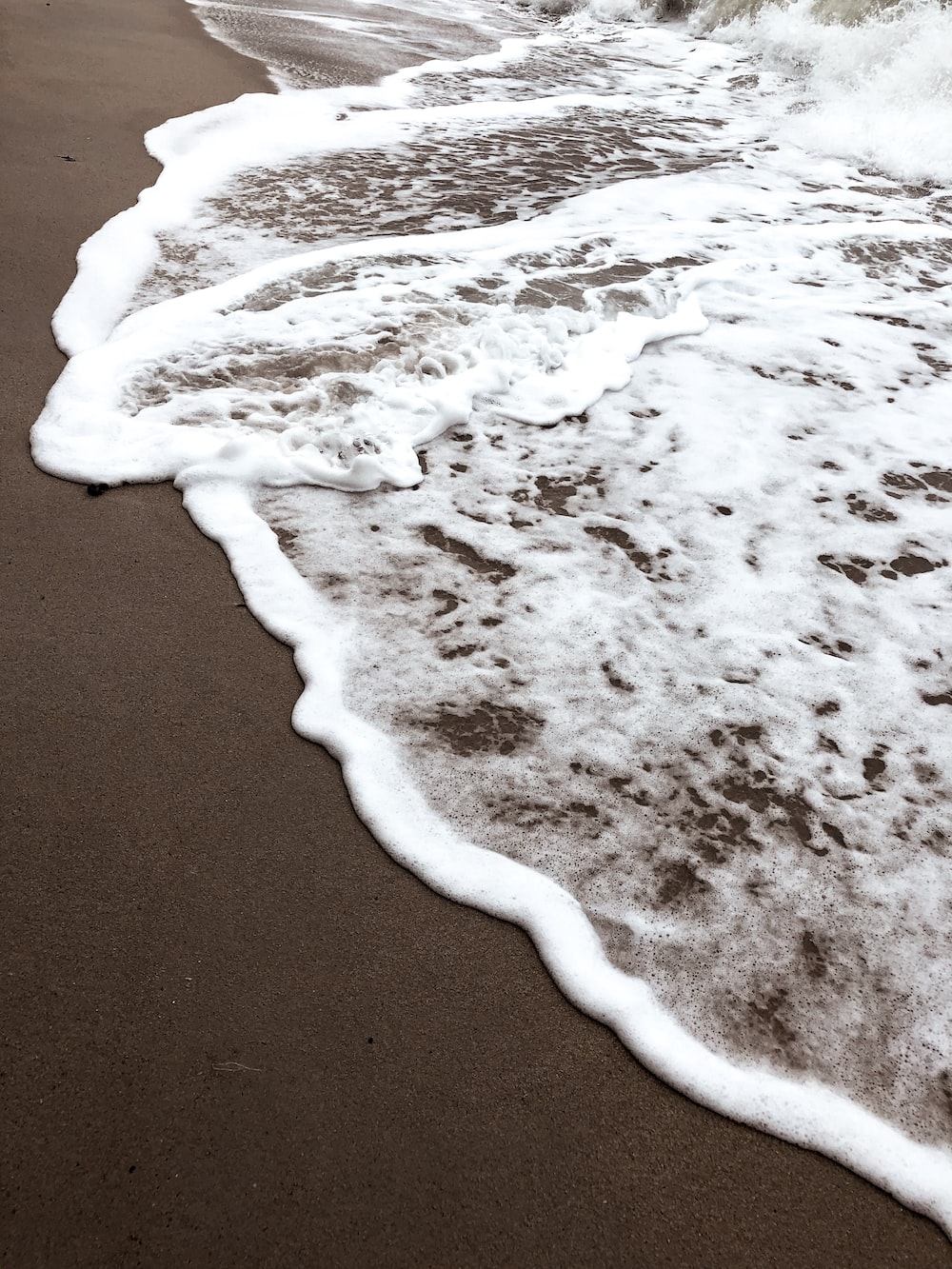 white and brown sea waves on brown sand photo
