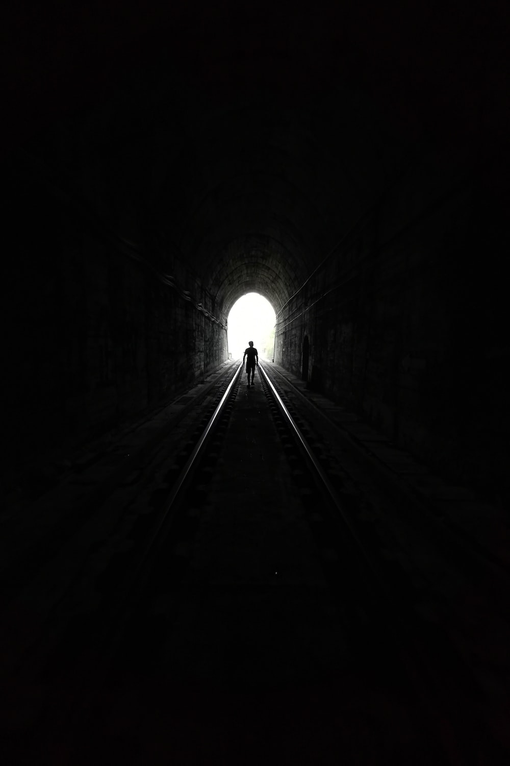 grayscale photo of tunnel with light photo