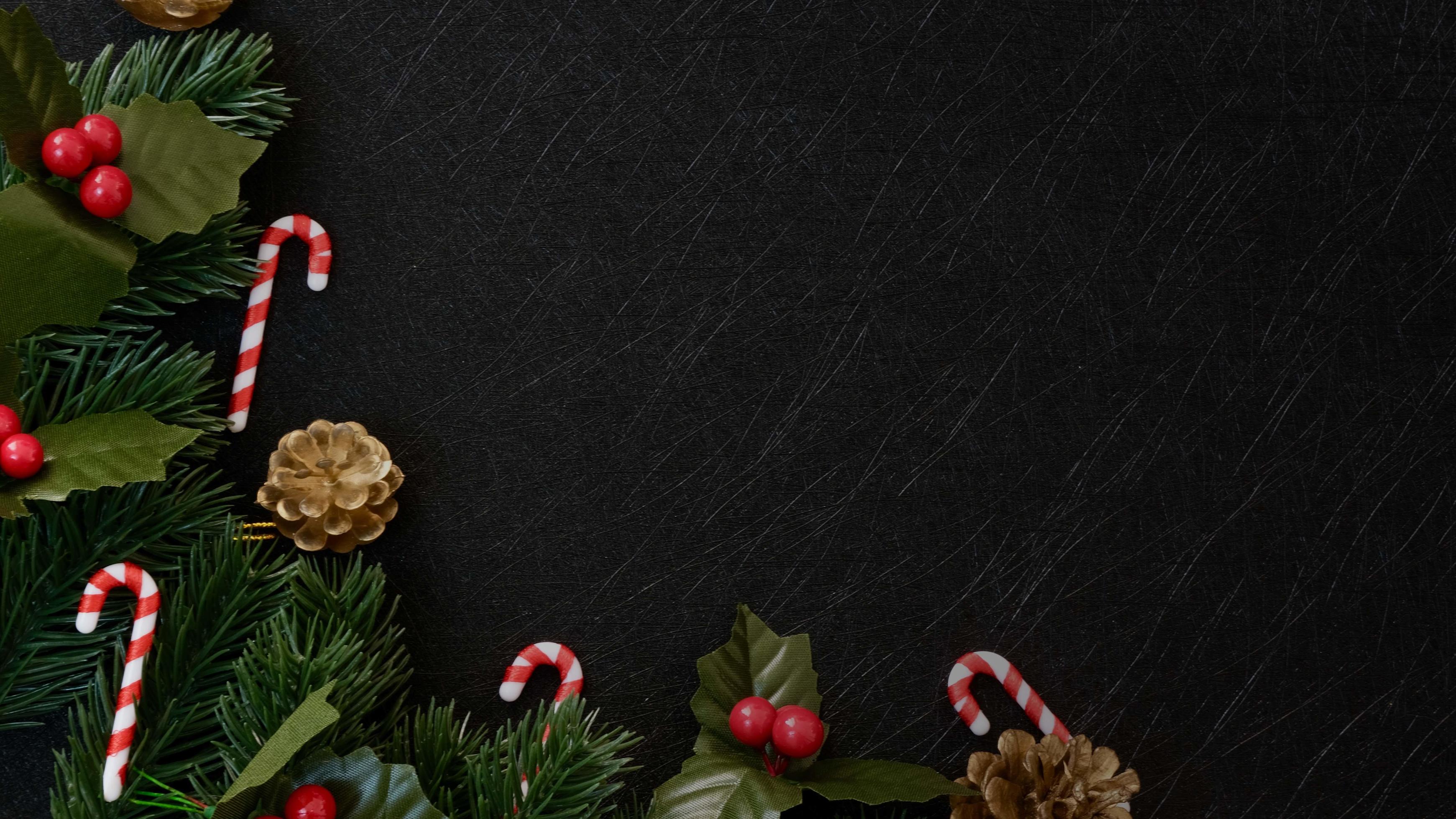 Top view christmas decorations, pine tree fir leaves, candy cane and red berries on dark black textured background