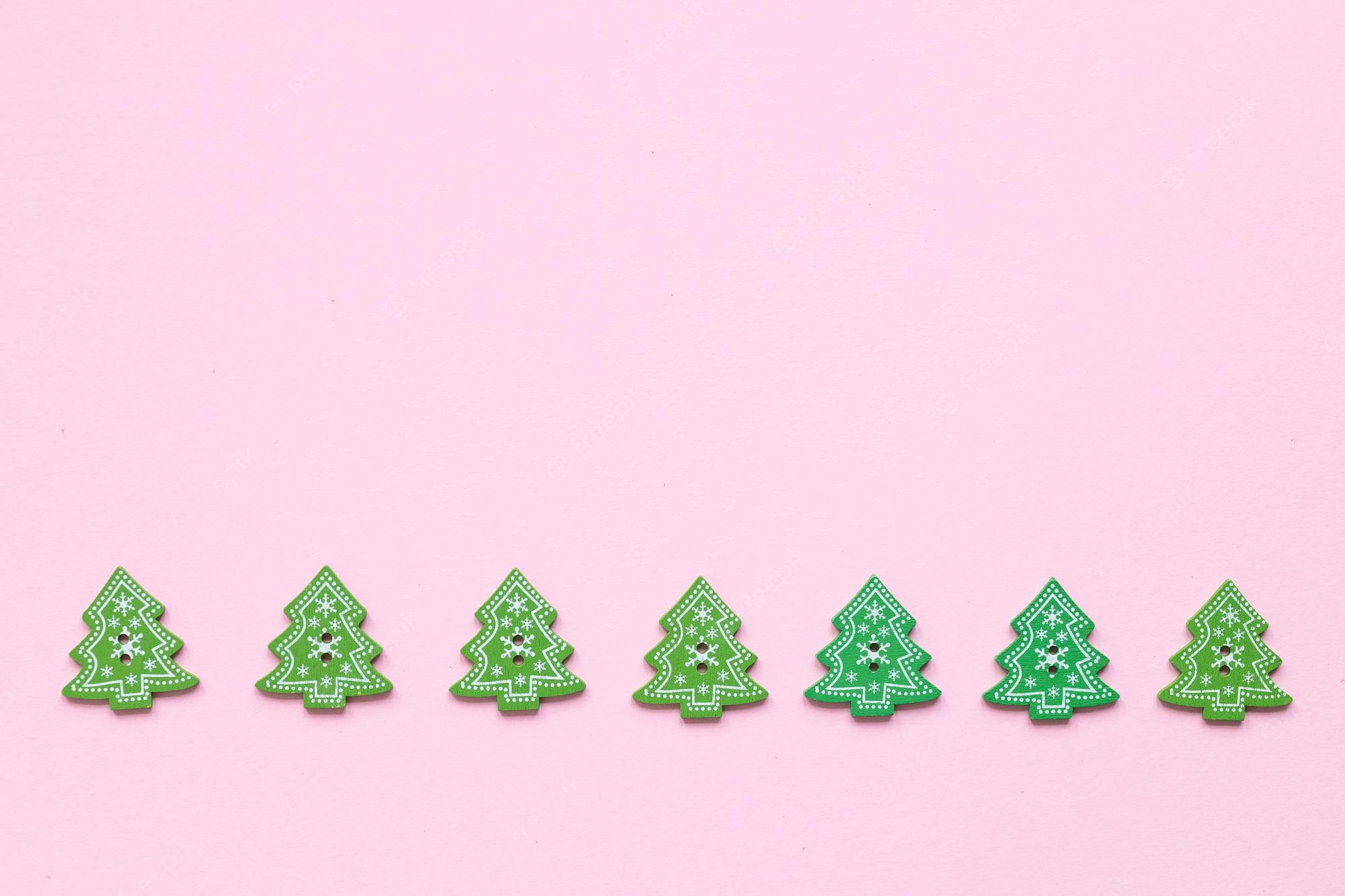 Premium Photo. Green wooden figures in the form of christmas tree on a pink background