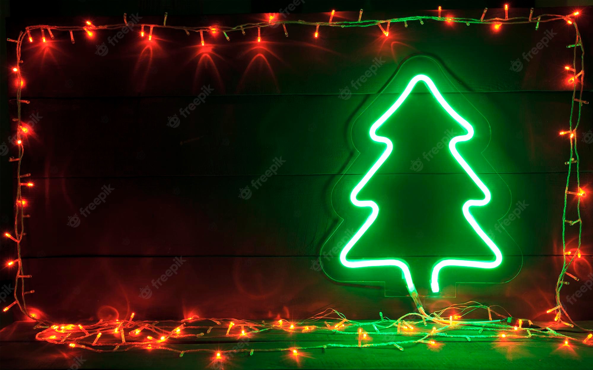 Premium Photo. The beautiful christmas background with a lot of lights and green neon christmas tree on the wooden desk