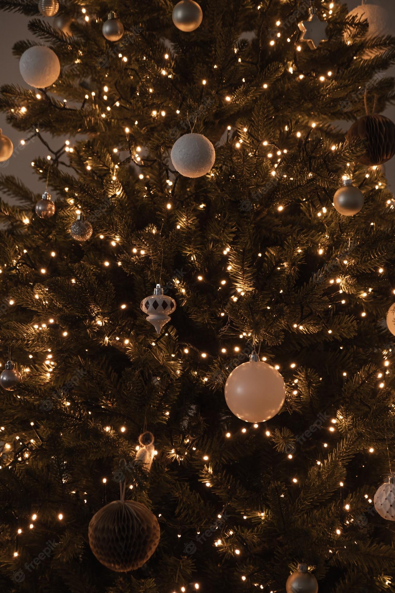 Premium Photo. Closeup of christmas tree decorated with glowing garland lights baubles minimal warm cozy christmas holidays background