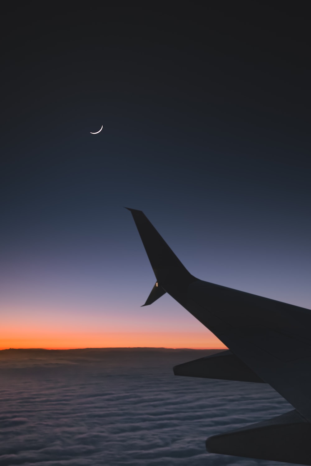 airplane flying over the clouds during sunset photo