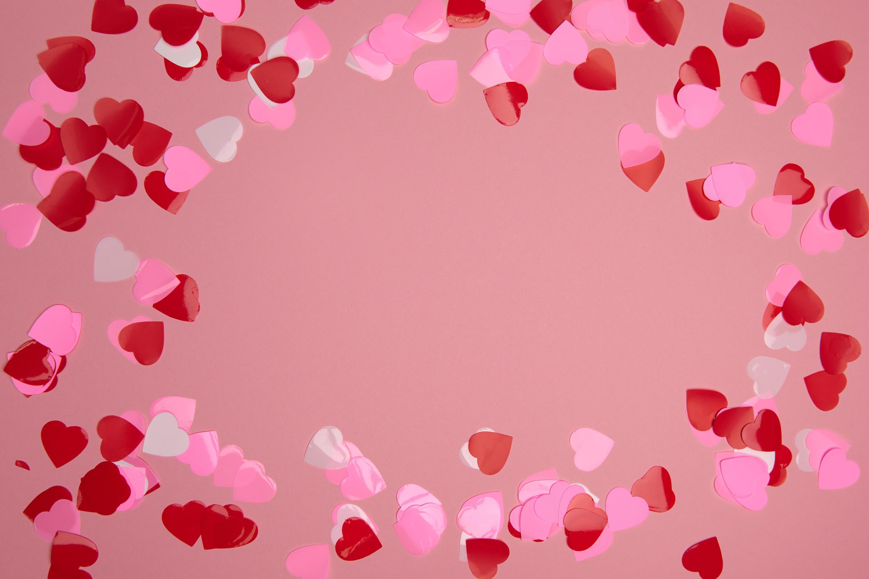 Valentine day composition. Confetti hearts red and pink on pastel background