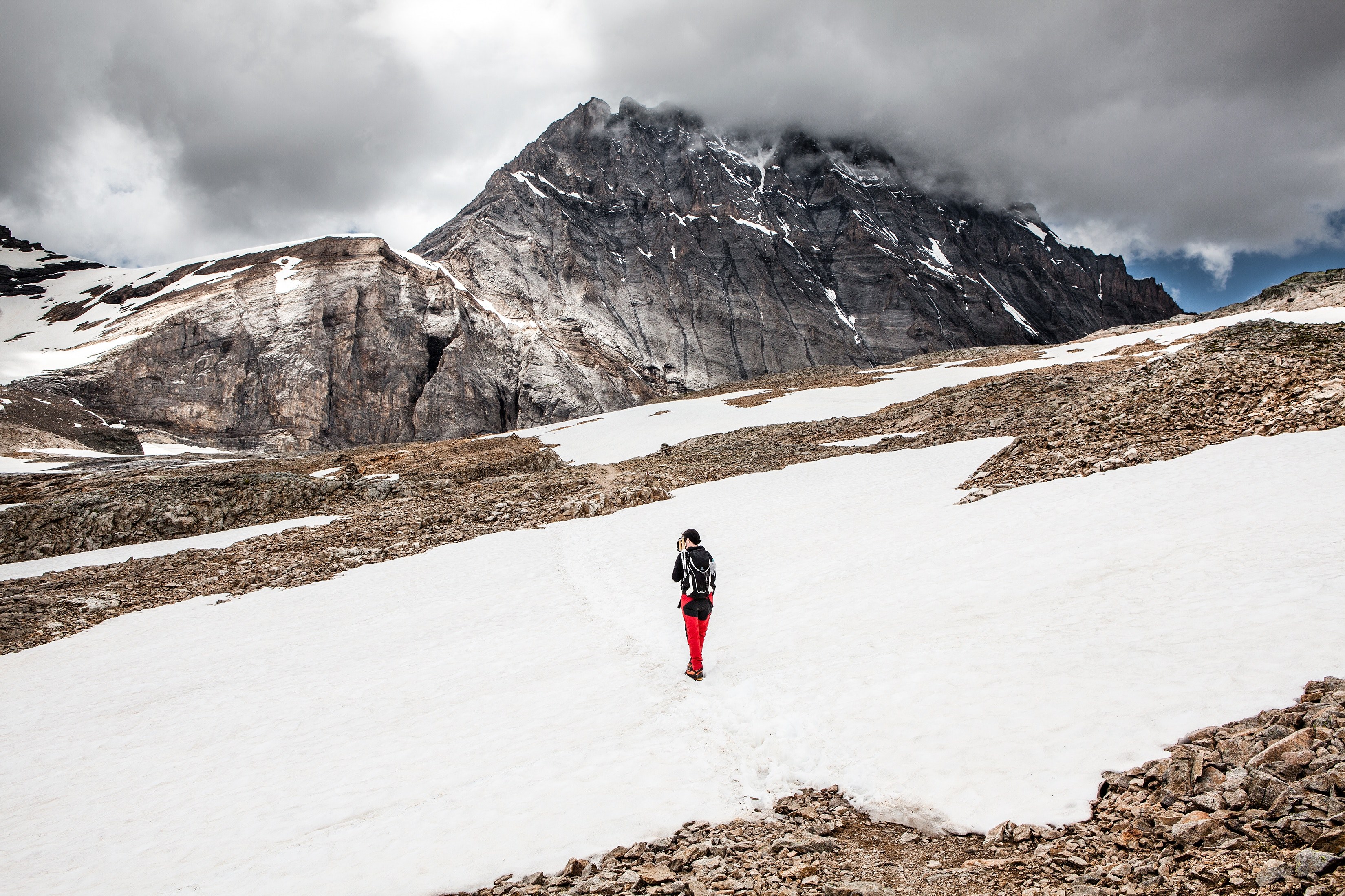 Wallpaper / a woman ascending down a winter mountain in switzerland, hiking in the swiss alps 4k wallpaper free download