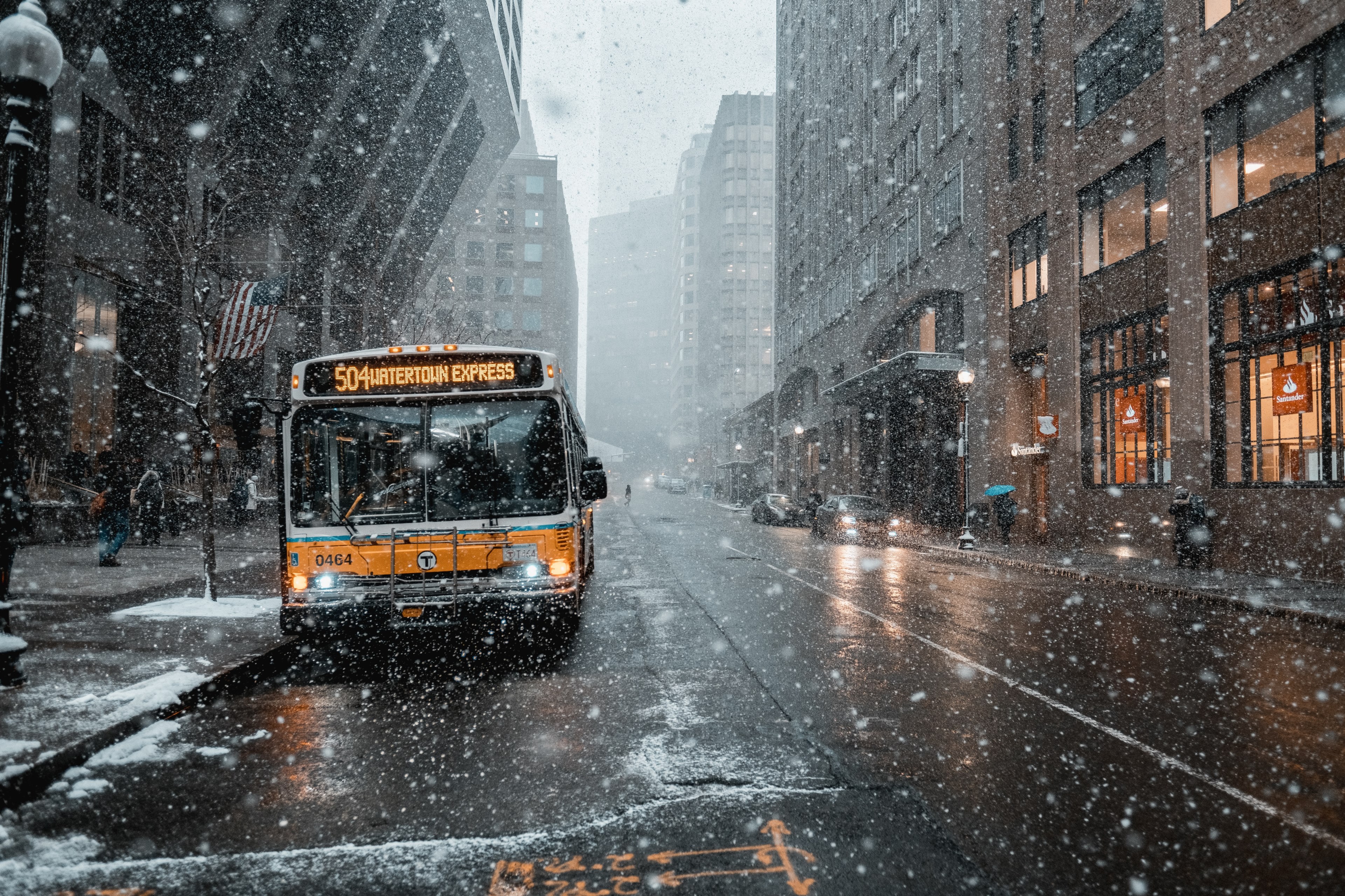 Wallpaper / a bus driving down the road in a populous city during a winter snowfall, city bus in winter 4k wallpaper free download