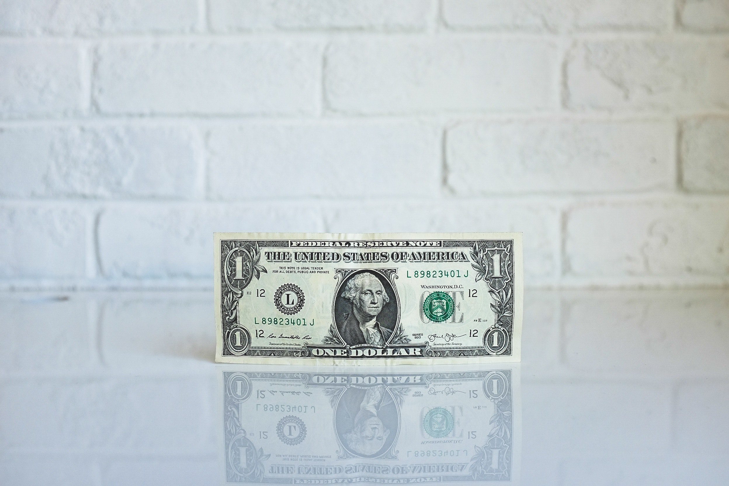 Wallpaper / a one dollar bill leaning against the wall on a glossy surface, one dollar bill by the wall 4k wallpaper free download