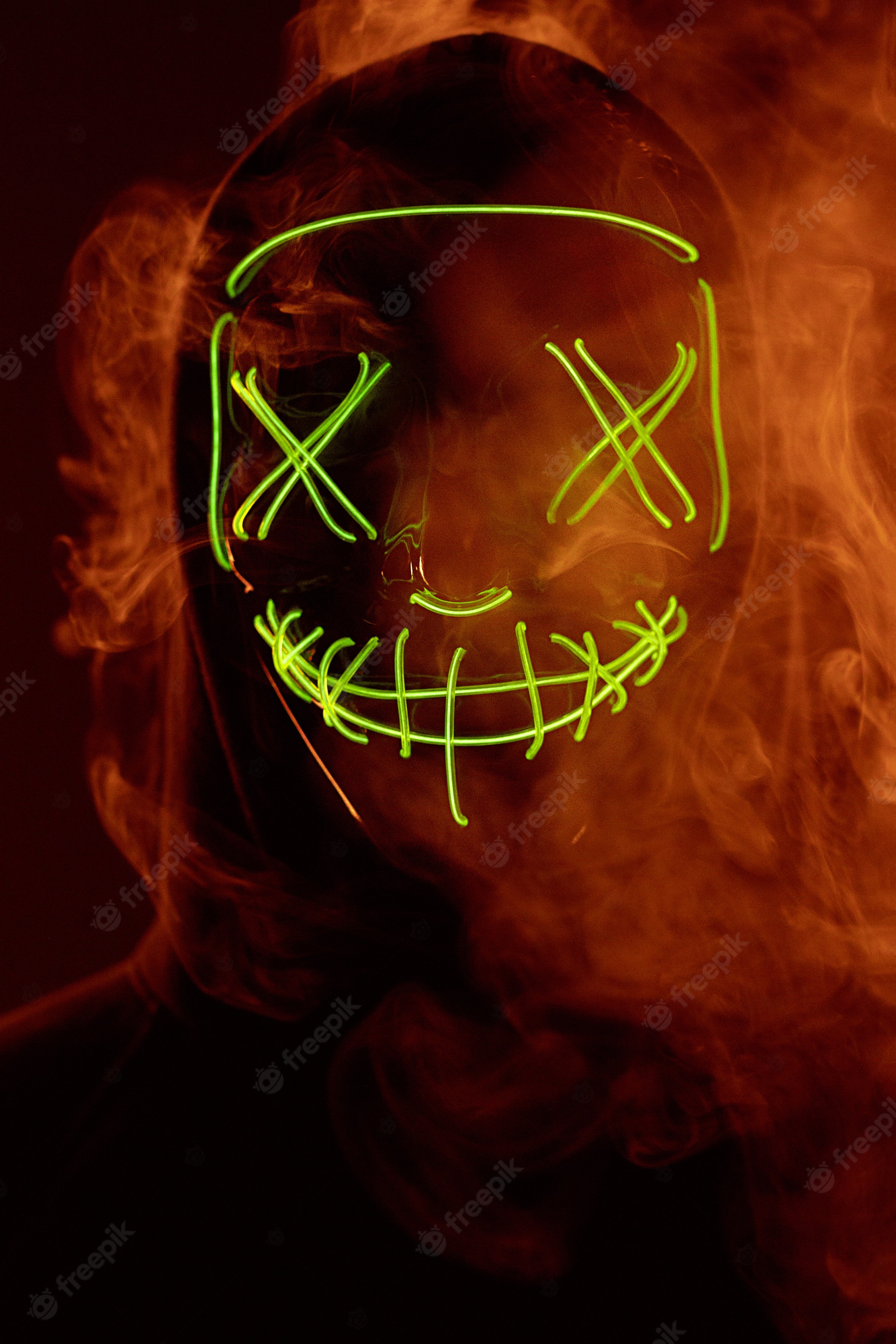 Premium Photo. Anonymous man hiding his face behind neon mask in a colored smoke