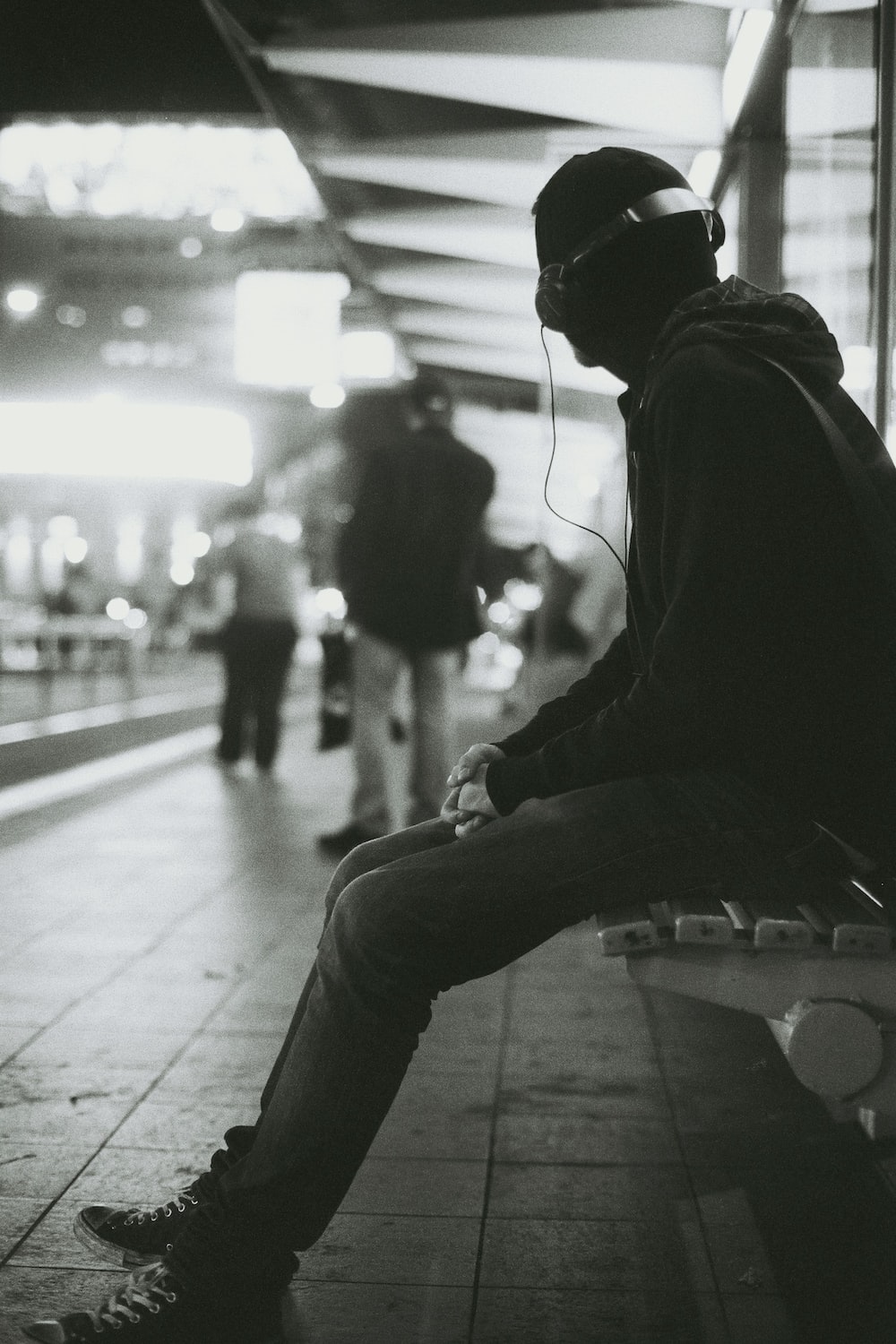 grayscale photography of a man sitting on bench while listening music photo