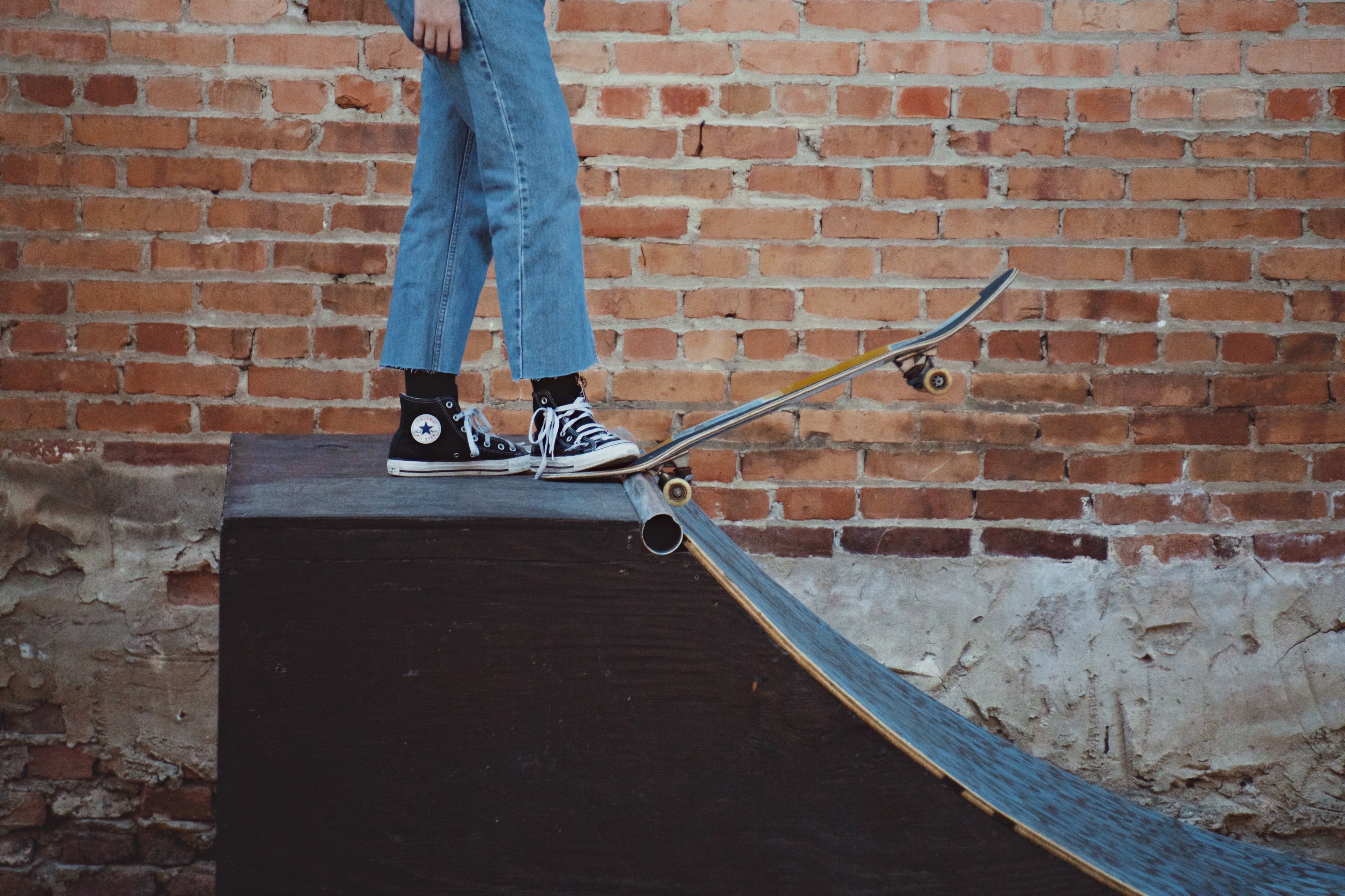 Wallpaper / kid in jeans and converse sneakers stepping on skateboard on a ramp edge in augusta common, skater kid in augusta common 4k wallpaper free download