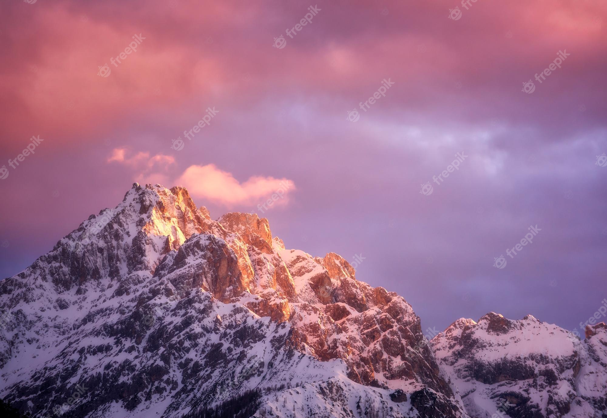 Premium Photo. Beautiful mountain peaks in snow and violet sky with pink clouds in winter at sunset colorful landscape with high snowy rocks cloudy purple sky in cold evening alpine mountains