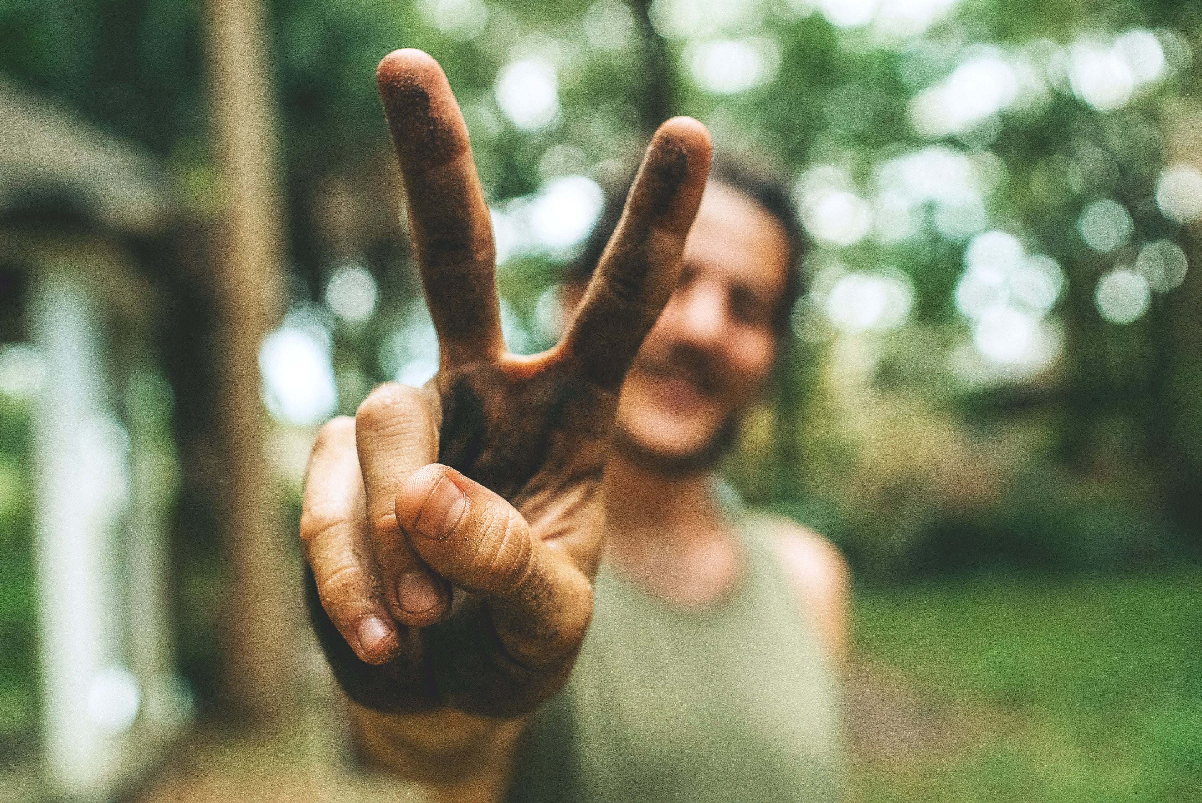 Wallpaper / man extends a peace sign with dirty hands in the wood, peace sign 4k wallpaper free download
