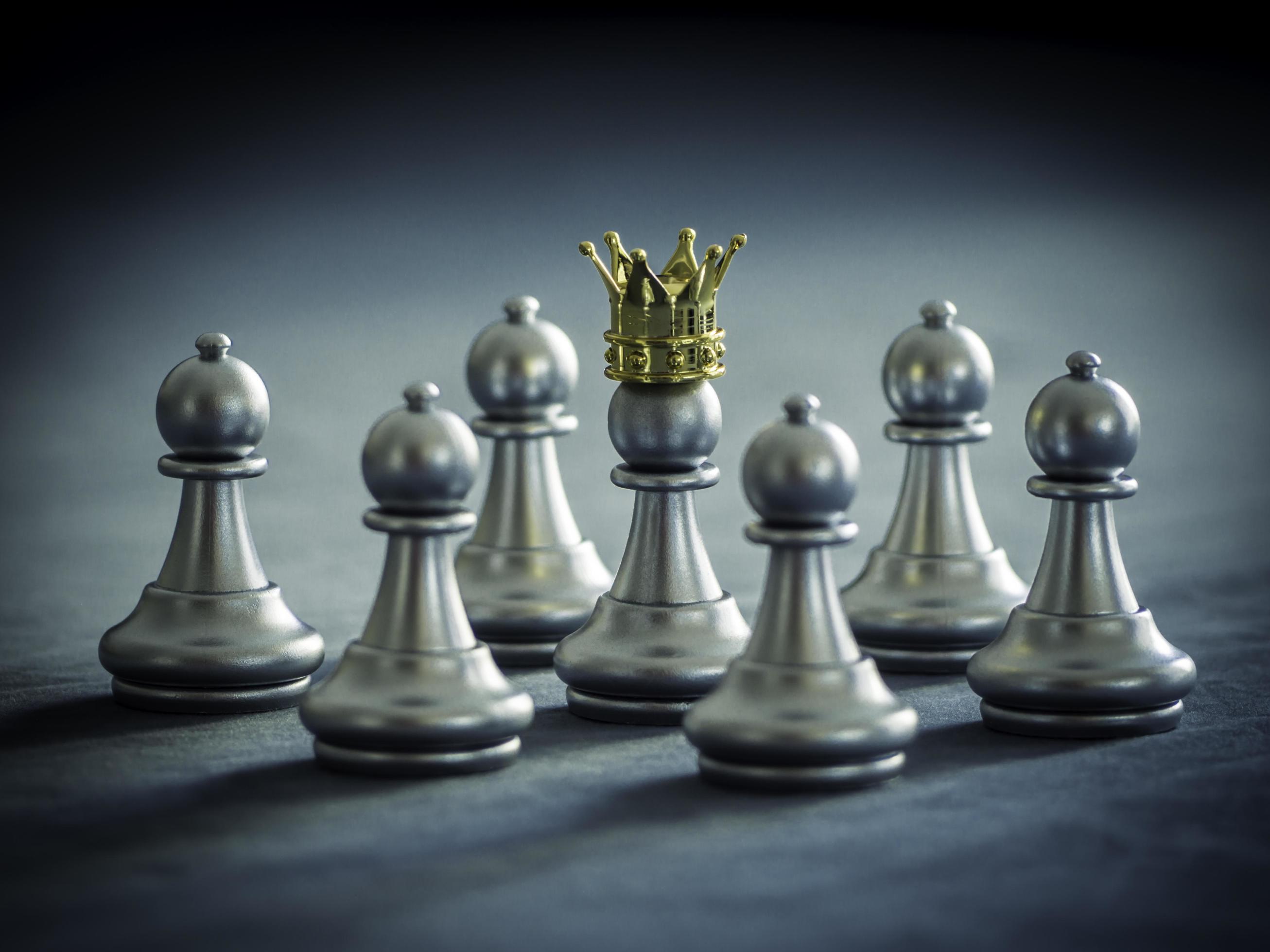 Silver chess pawn wear gold crown is surrounded by falling around silver chess pieces to fighting with teamwork to victory, business strategy concept and leader and teamwork concept for success. 7132972 Stock