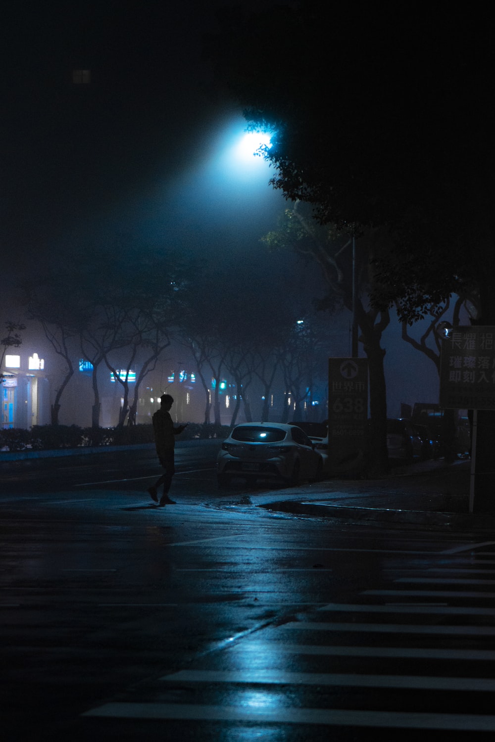 man walking on street during night time photo