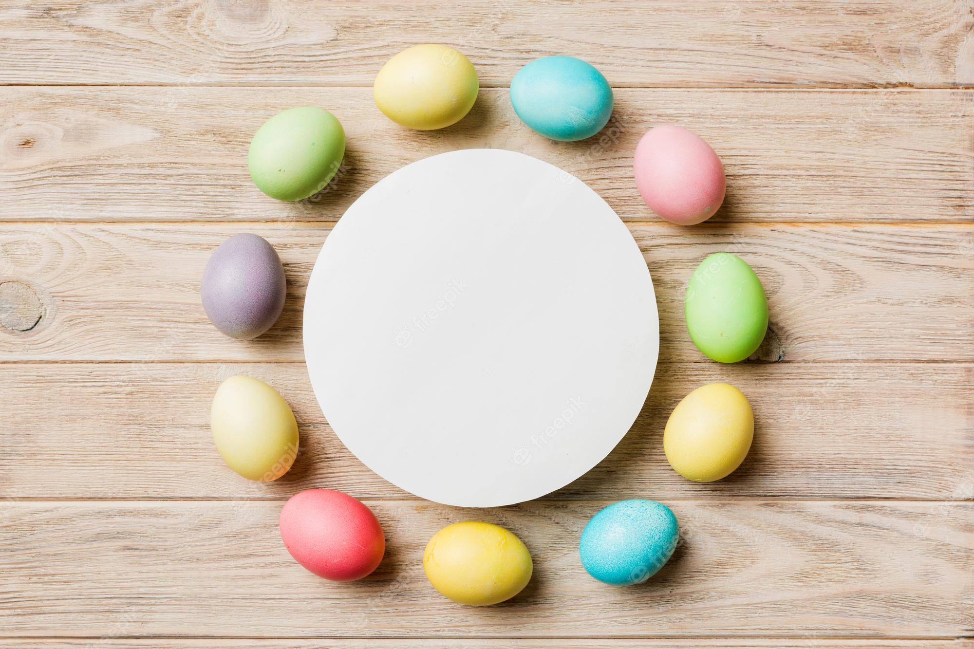 Premium Photo. Round frame multicolored easter eggs with white blank paper on a brown background closeup space for text blank for design selective focus tinted image