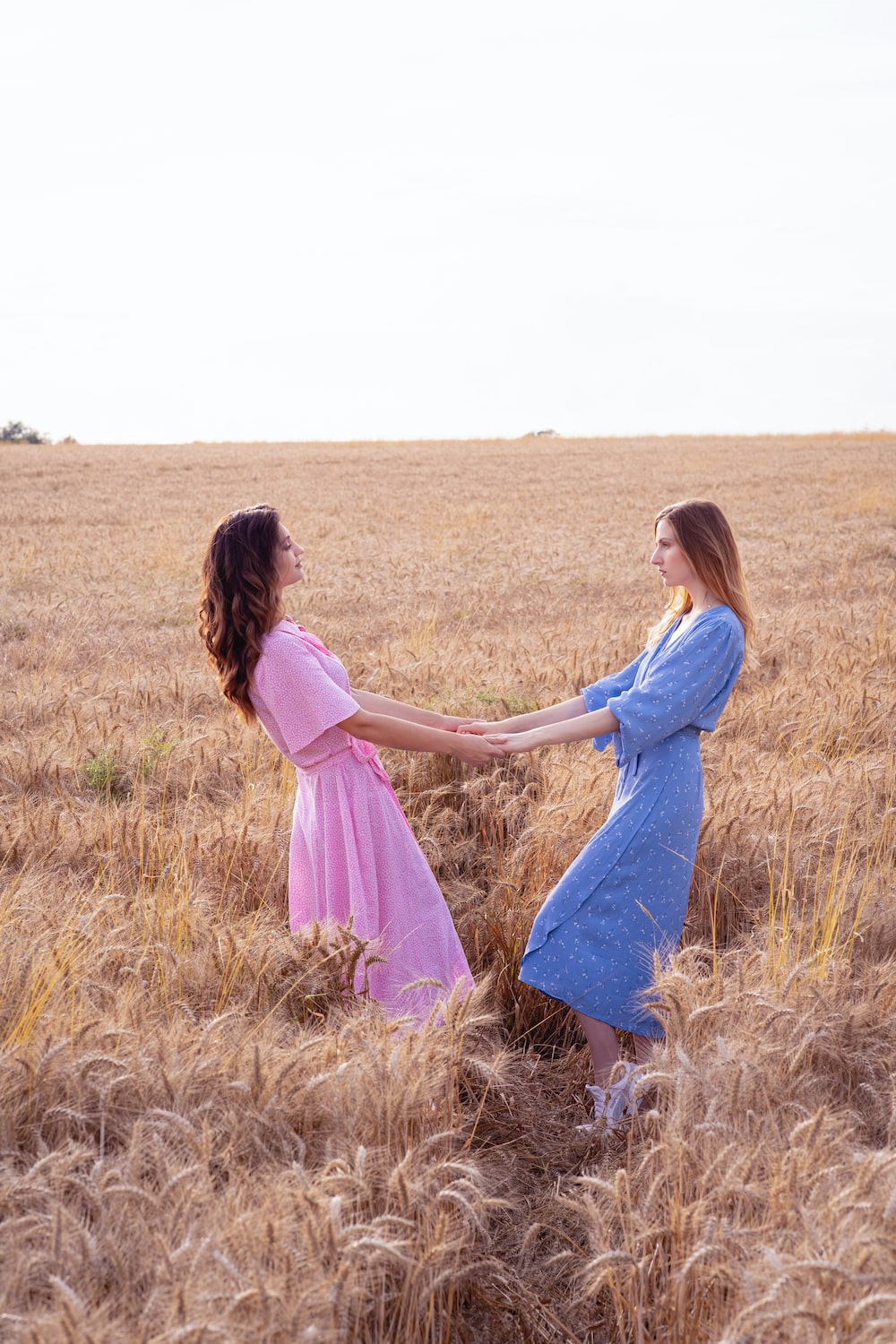 two women in a field holding hands photo