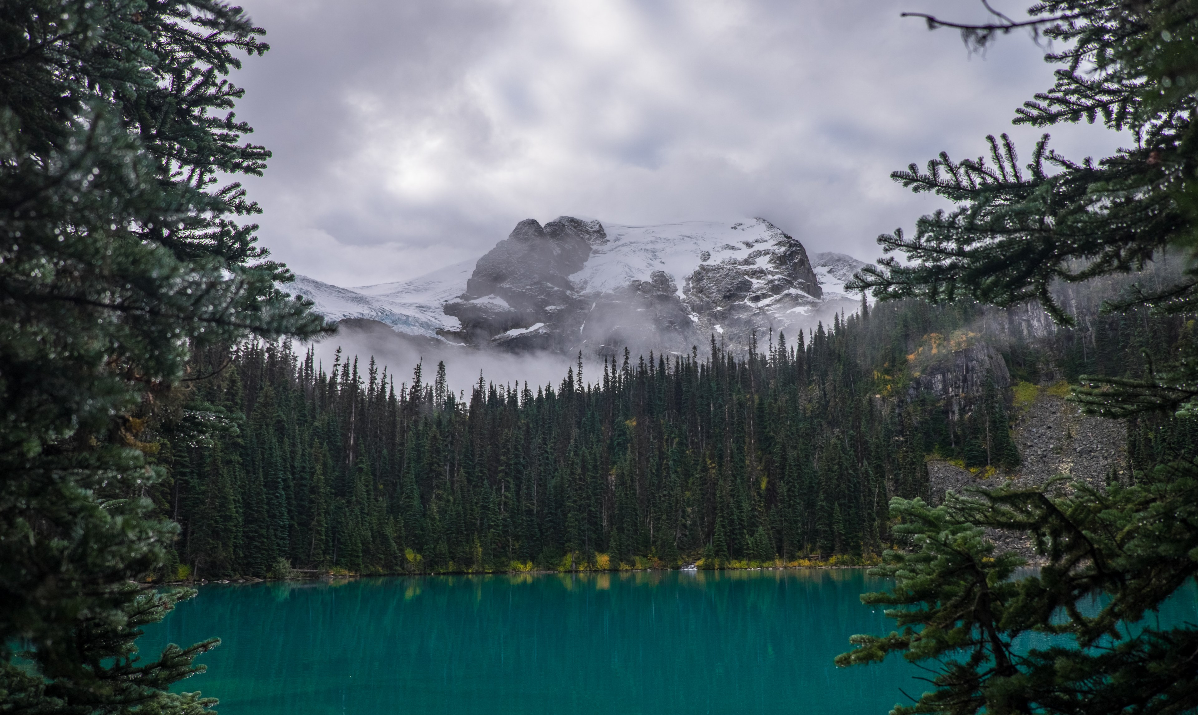 Wallpaper / a hidden lake with forests surrounding it and snow covered mountain in the background with a cloudy sky in joffre lakes trail, _hiking joffre lakes in british columbia