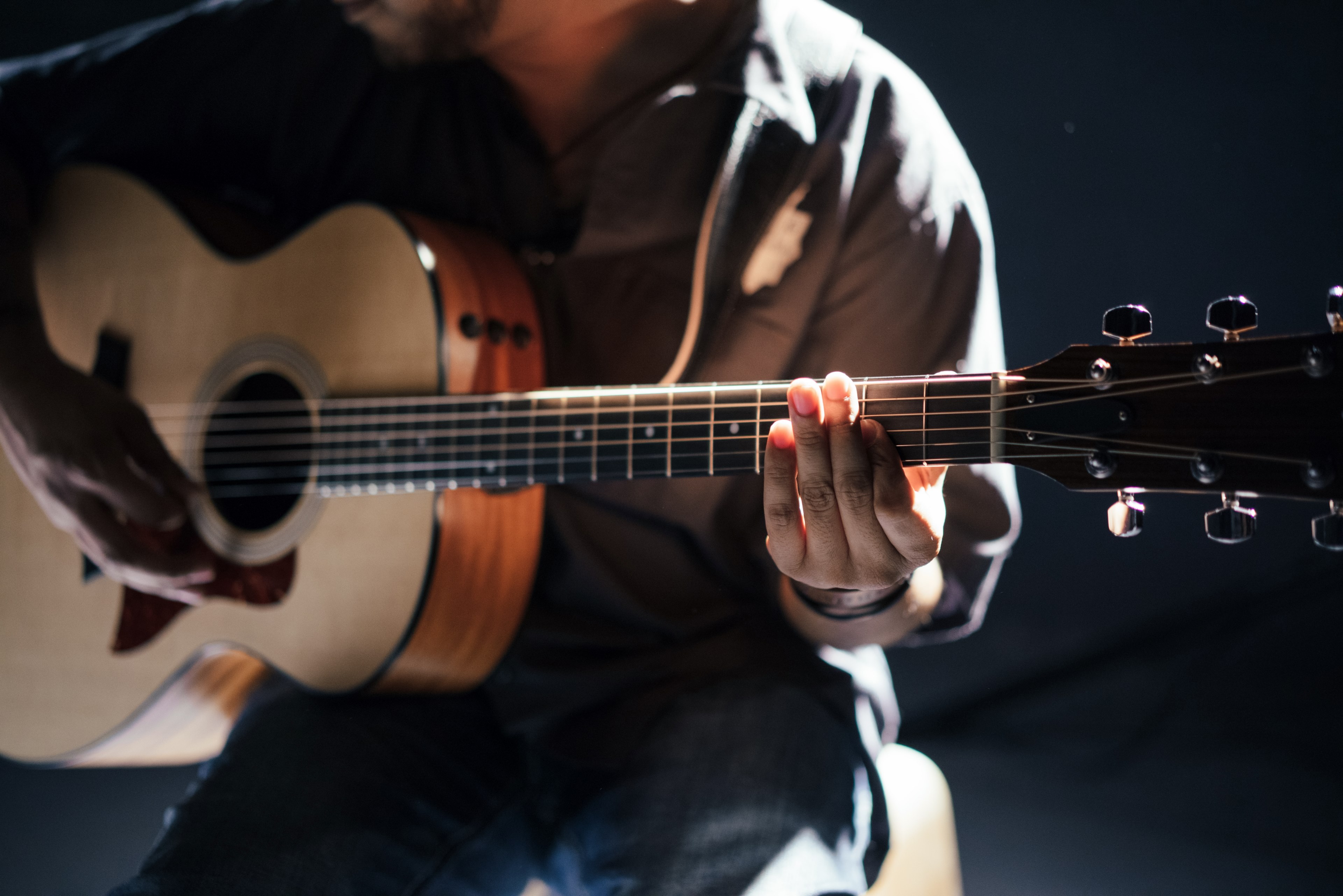 Wallpaper / a seated person playing acoustic guitar, acoustic guitar player in pale light 4k wallpaper free download