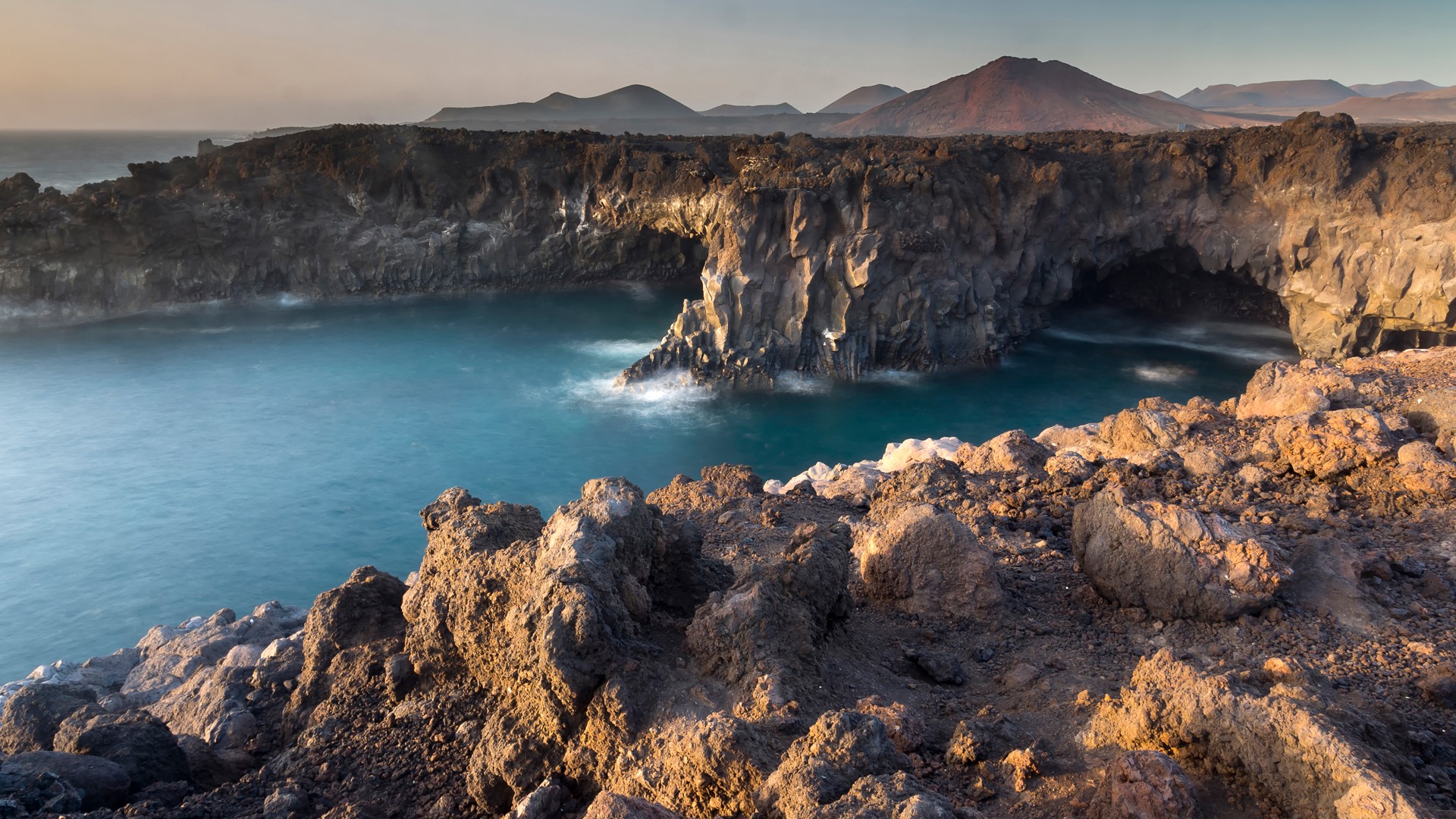 Lava cliffs and volcano skyline, Timanfaya National Park, Lanzarote, Canary Islands, Spain. Windows 10 Spotlight Image