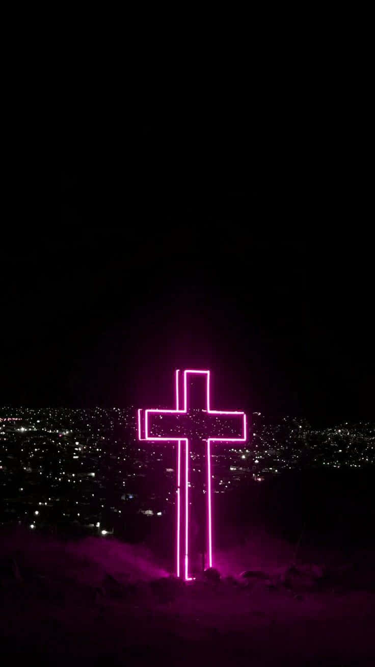 Download A Pink Cross On A Hill With A City In The Background Wallpaper