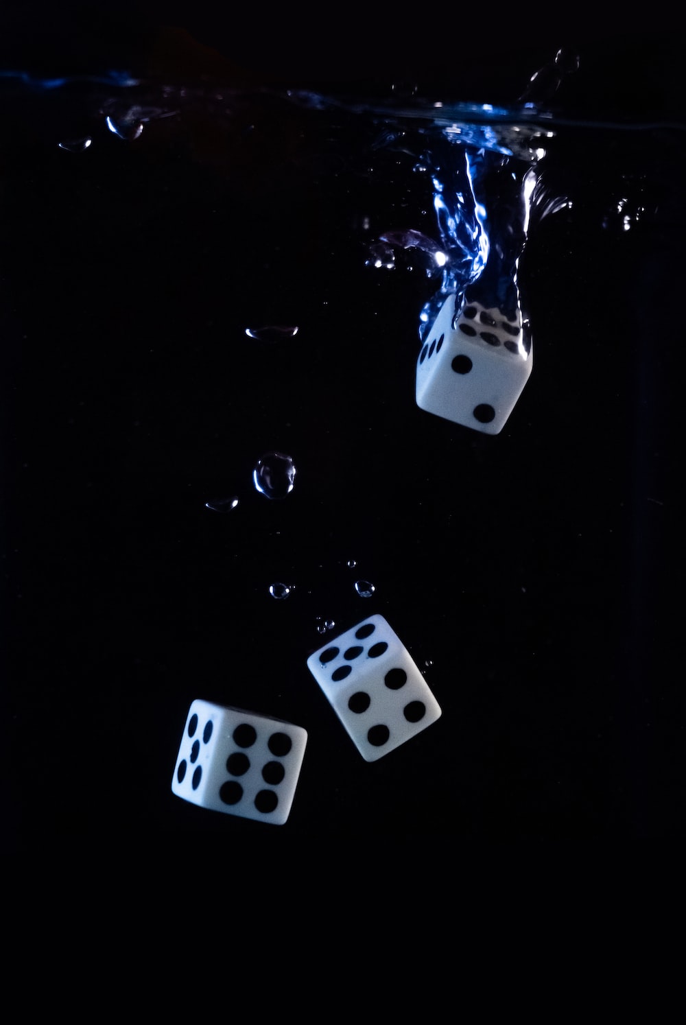 three dices floating in the water on a black background photo