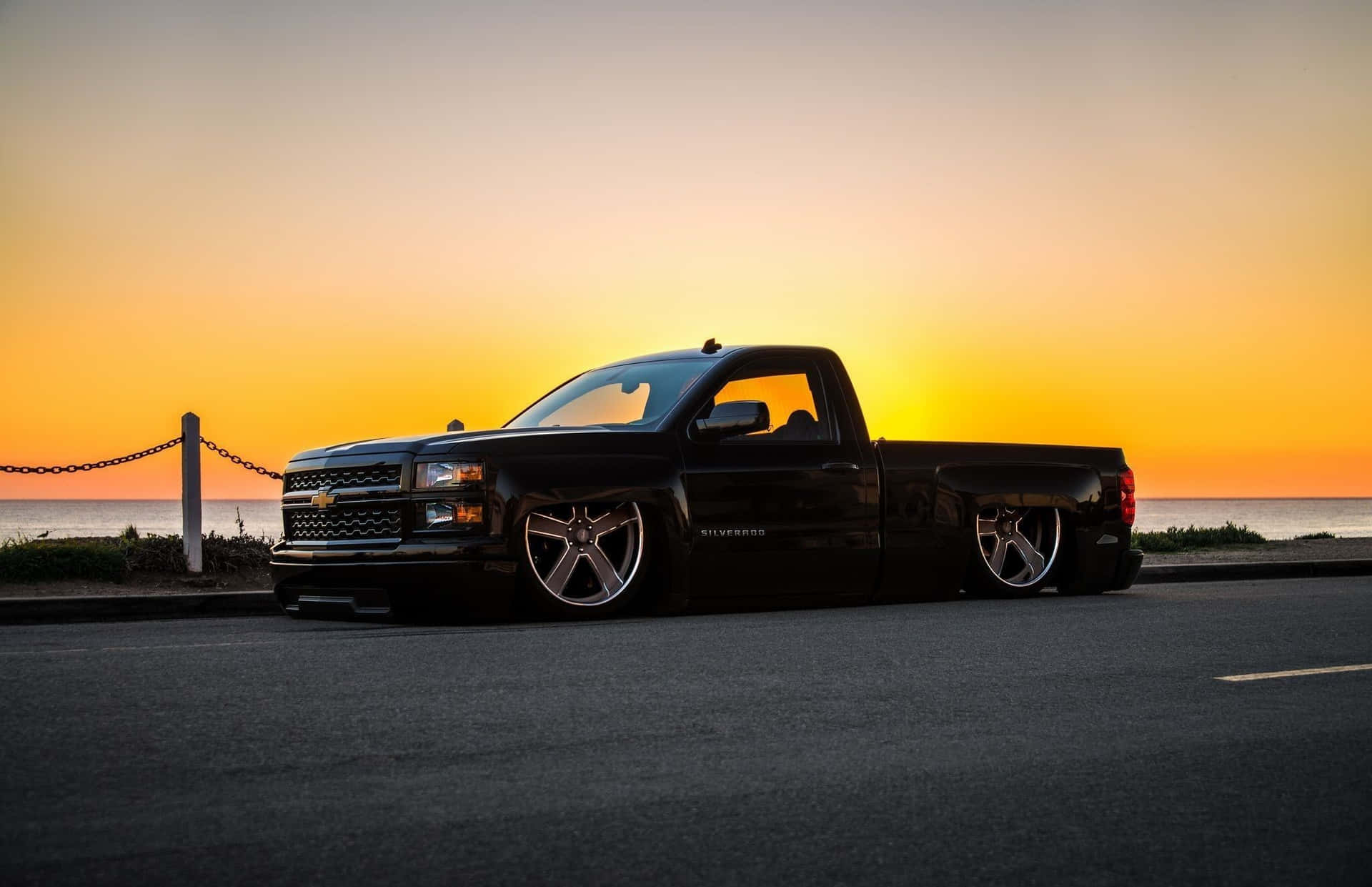 Download A Black Pickup Truck Parked On The Side Of The Road Wallpaper
