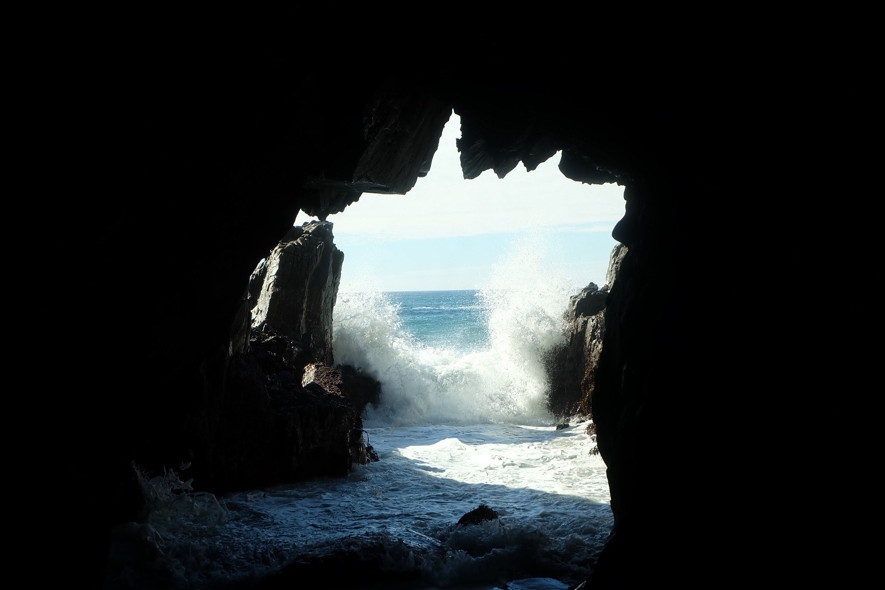 Wallpaper / sea waves splashing at the entrance to a dark sea cave, sea cave entrance 4k wallpaper free download