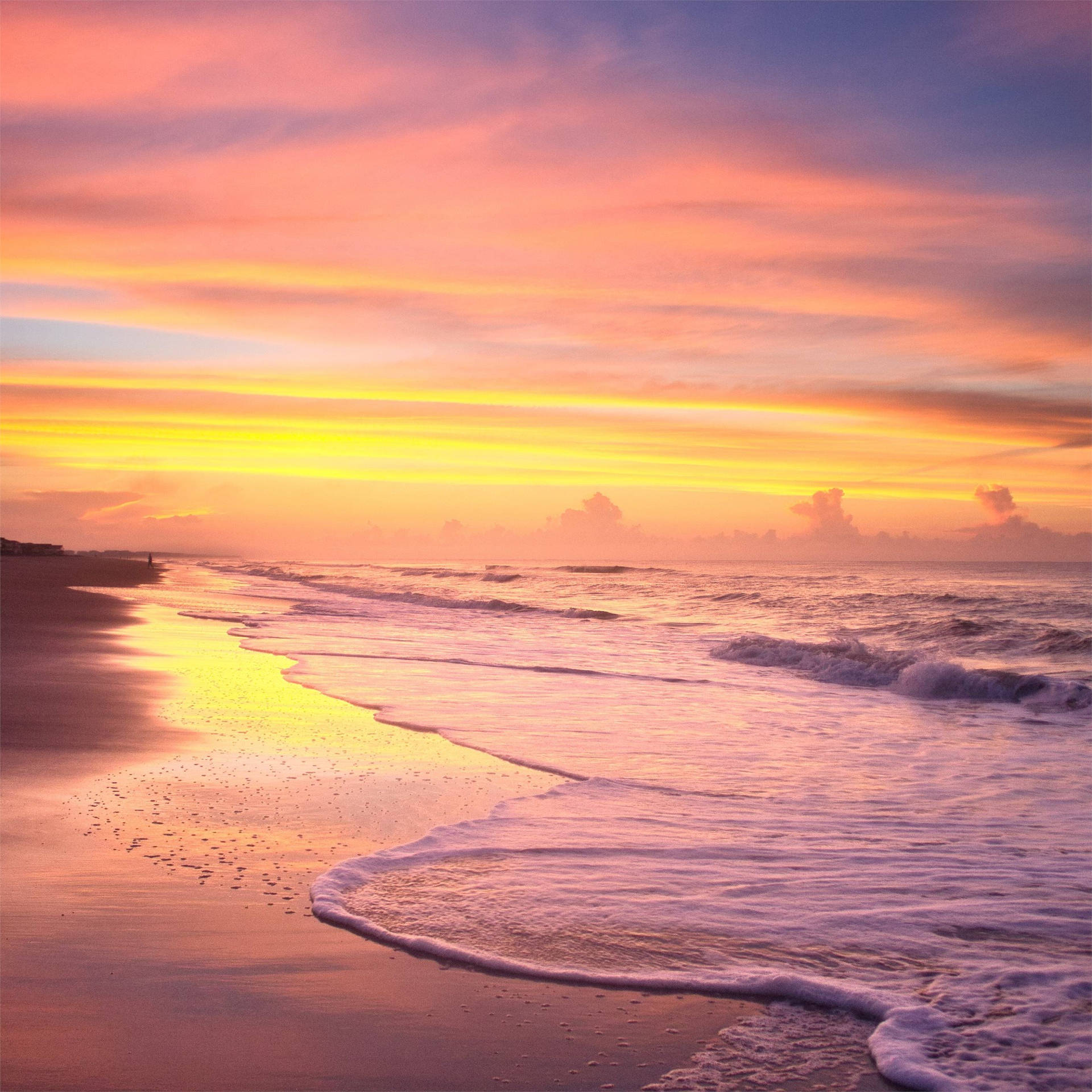 Download A Beach With Waves And A Sunset Wallpaper