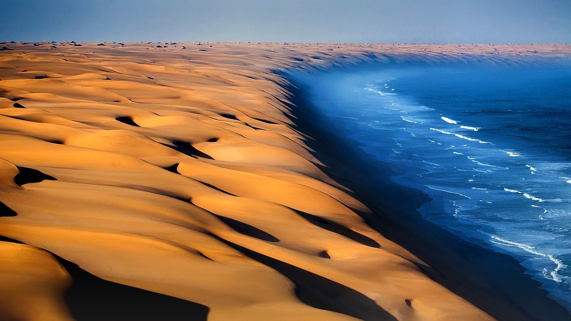 Dunes of the Namib Desert meet the Atlantic Ocean, Namibia, Africa. Windows 10 Spotlight Image