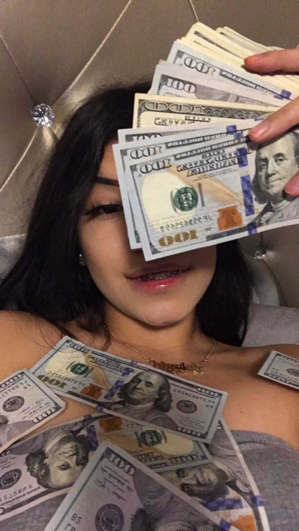 Download A Girl Laying On A Bed With A Bunch Of Money Wallpaper