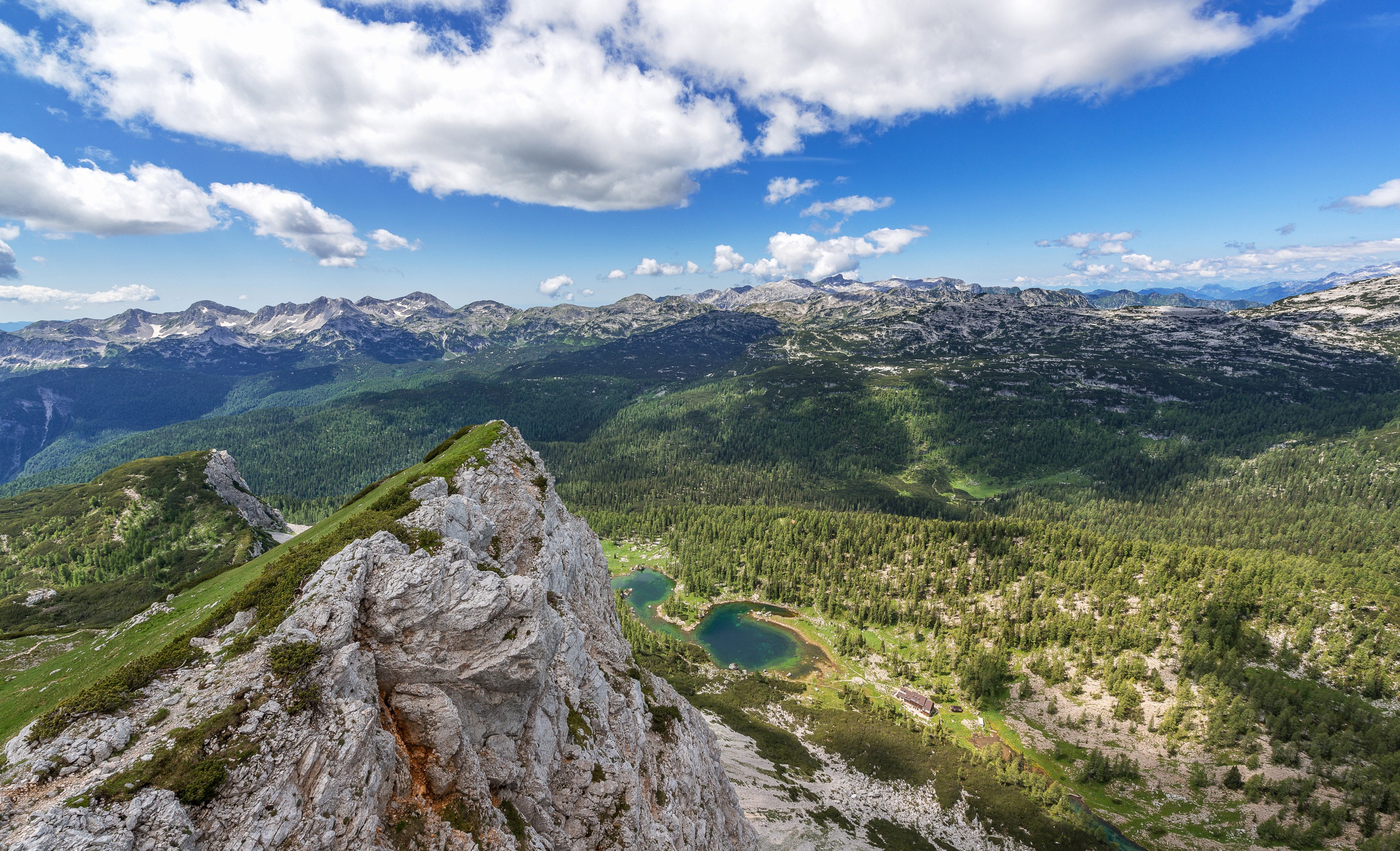 Wallpaper / a mountaintop view on a small lake and wooded mountains in triglav national park, woods seen from a mountain 4k wallpaper free download