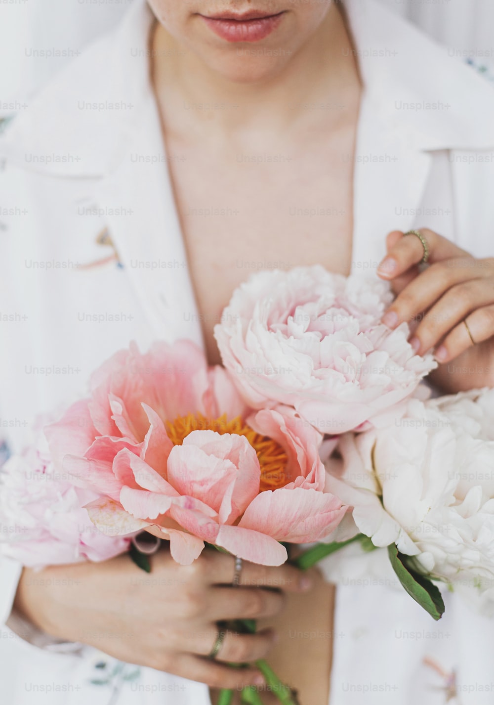 Beautiful stylish woman holding peony bouquet. young female in boho floral shirt gently holding pink and white peony flowers in hands. sensual soft image. spring aesthetics photo