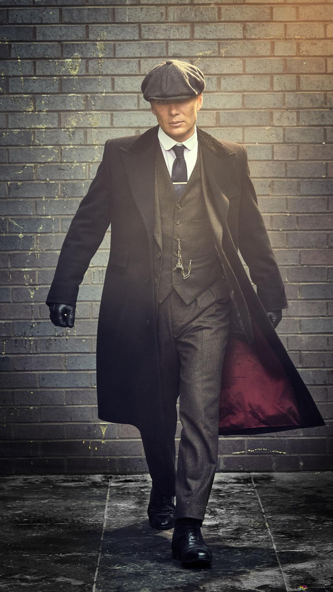 Portrait of peaky blinders tv series character with long overcoat and suit in front of wall 2K wallpaper download