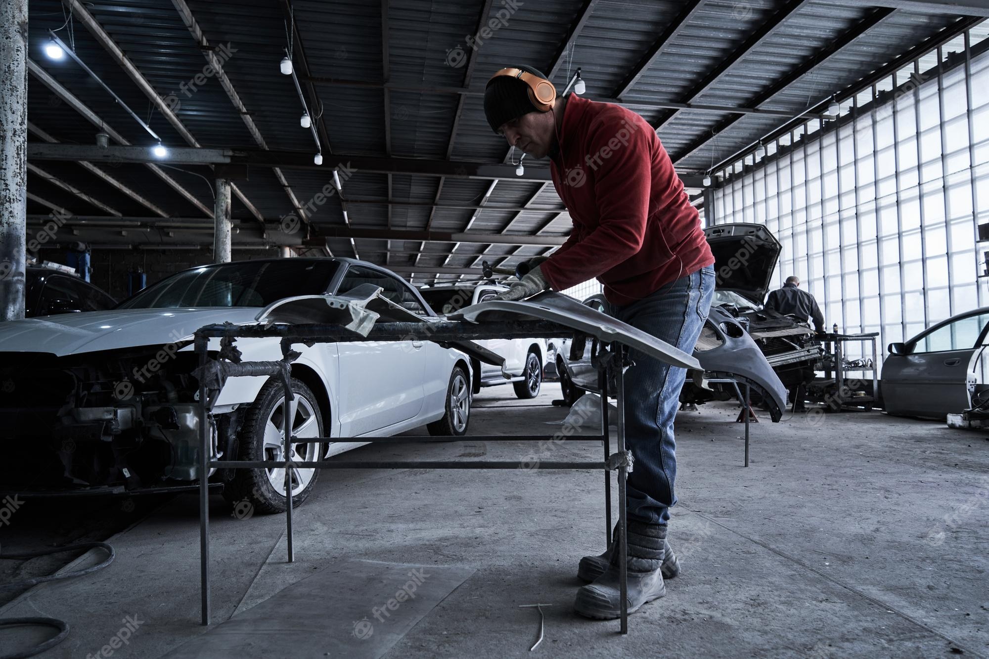 Premium Photo. Car service worker repairs restores car