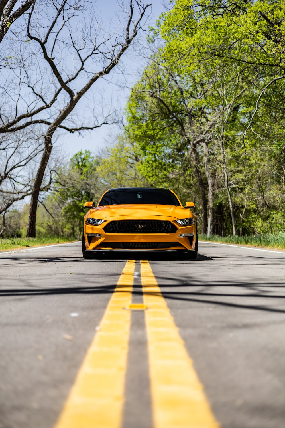 A yellow ford mustang parked on the side of the road photo