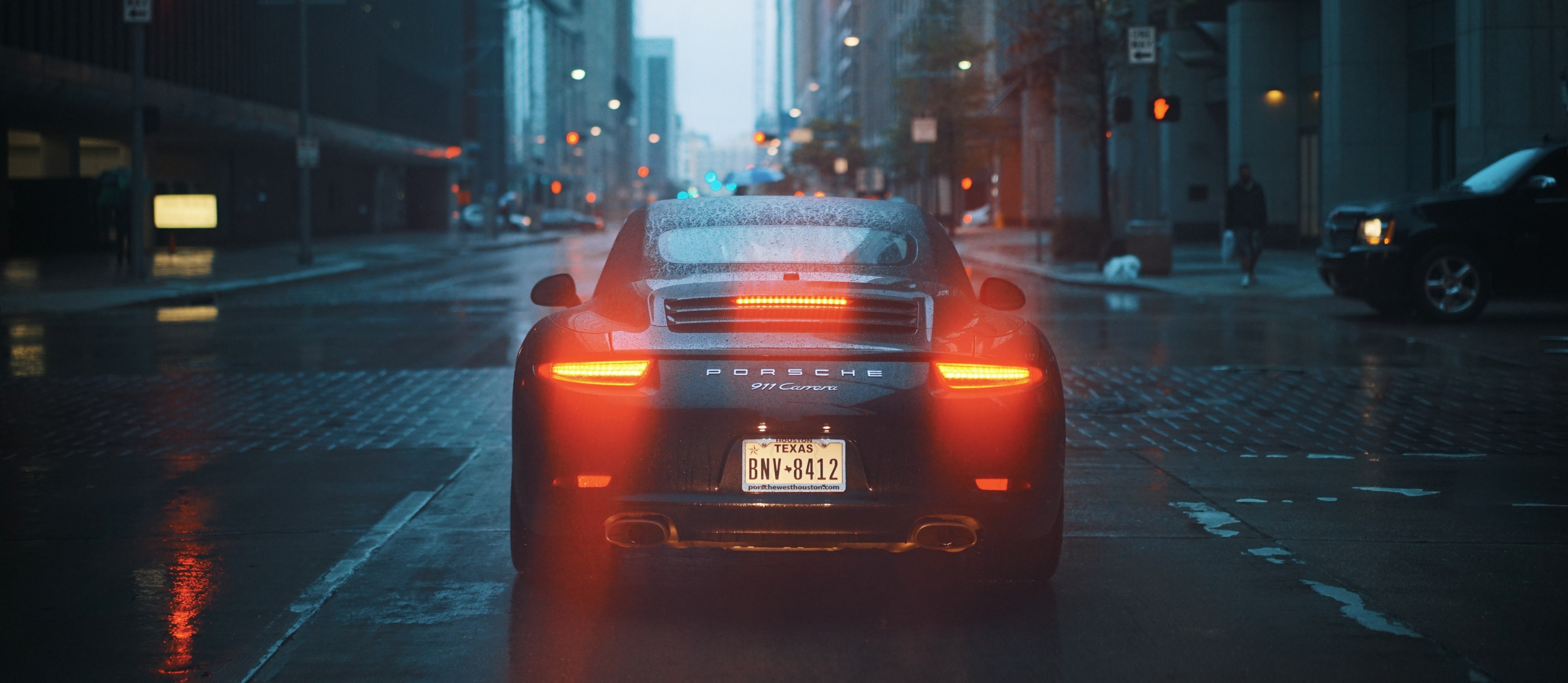 Wallpaper / the back of a black porsche 911 with its tail lights on on a wet street, porsche 911 on a rainy evening 4k wallpaper free download