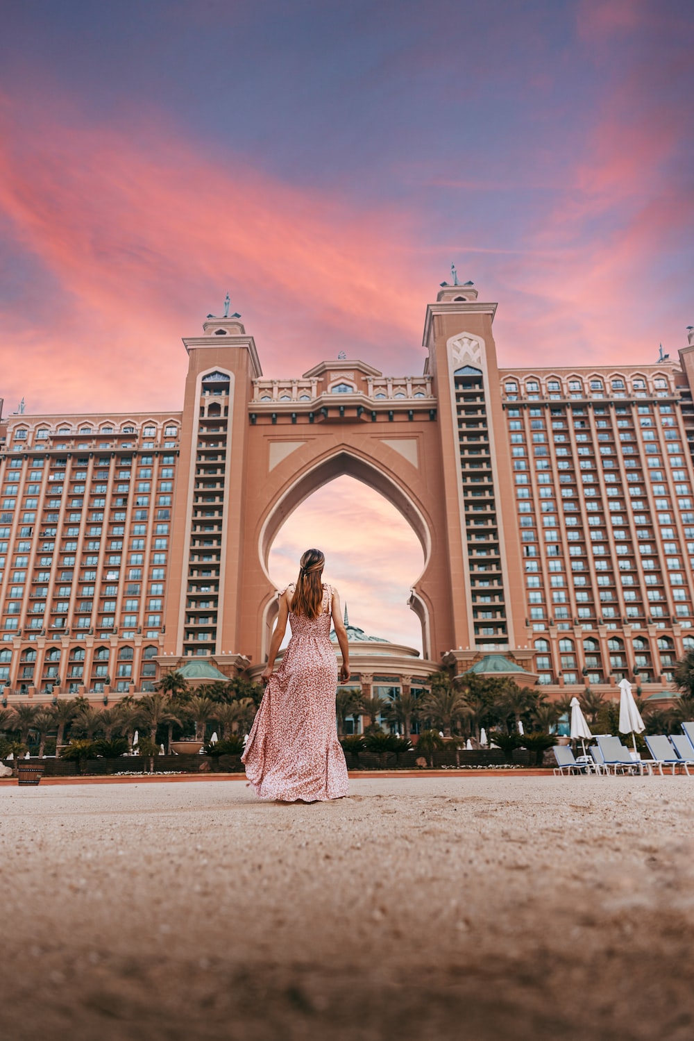 A person in a dress standing in front of a large building with atlantis, the palm in the background photo