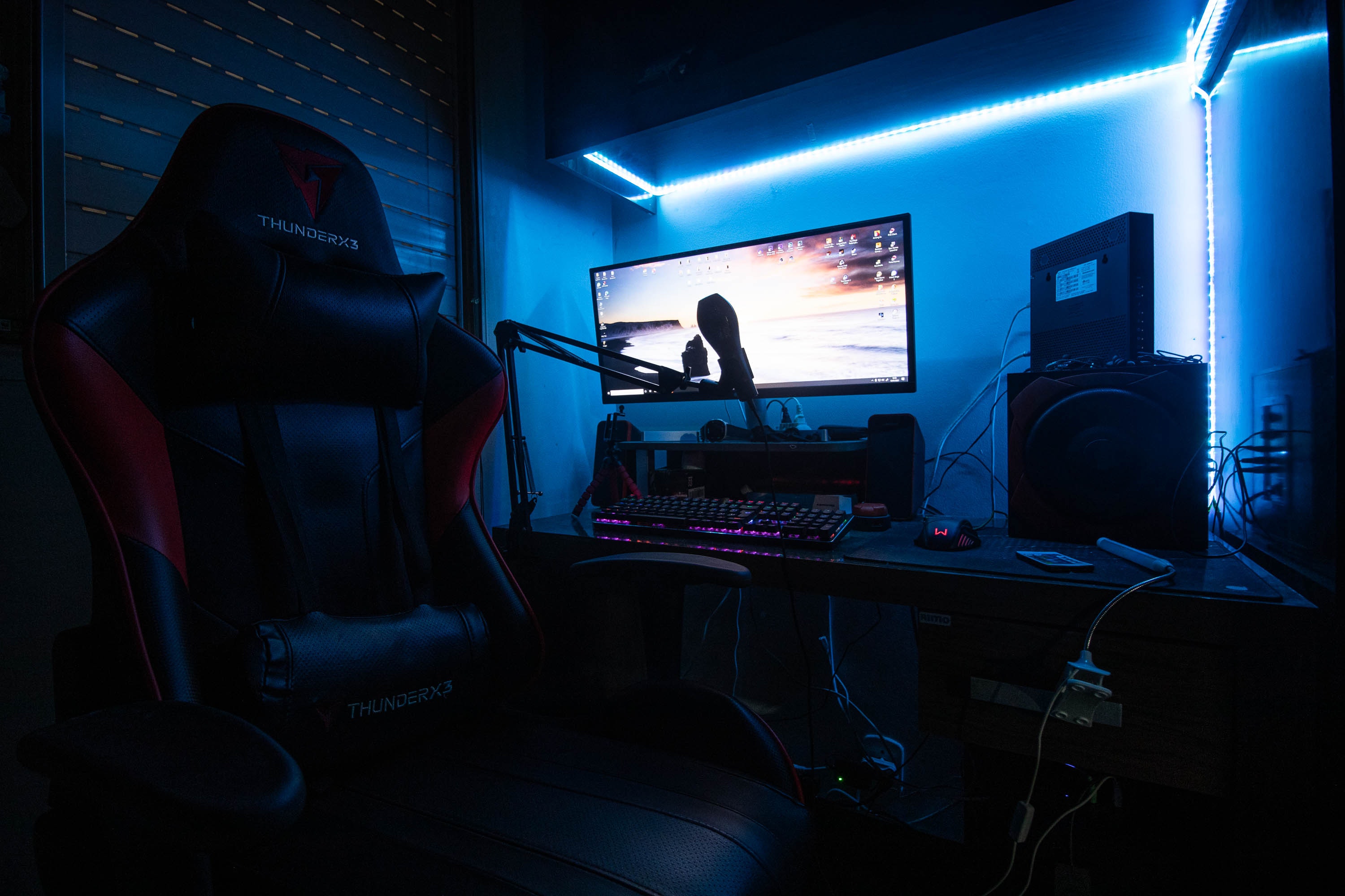 Desktop Computer with Speakers and Gaming Chair in a Room with Blue Light · Free