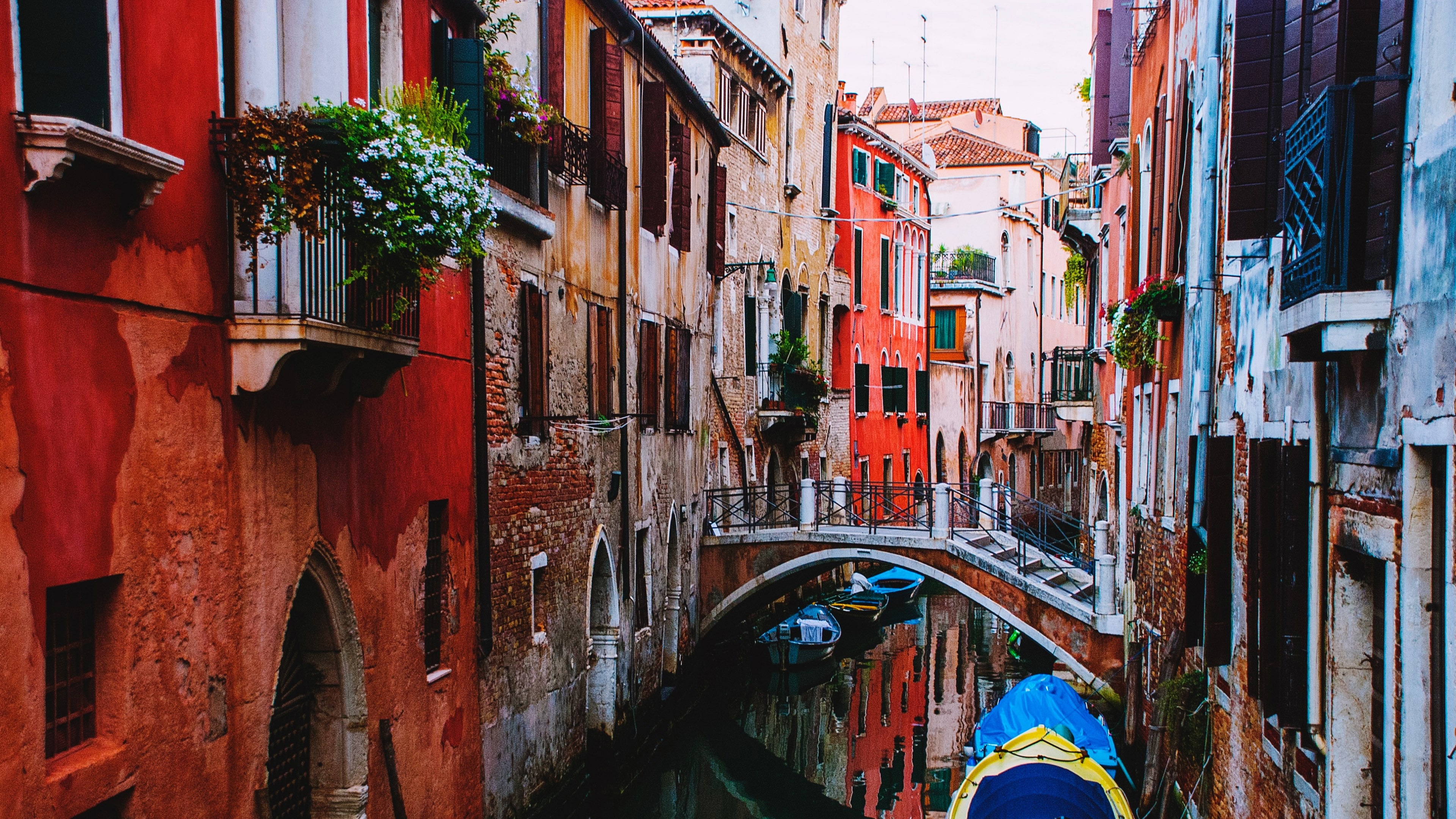Wallpaper / a canal with a bridge between red brick buildings in venice, red venice canal 4k wallpaper free download