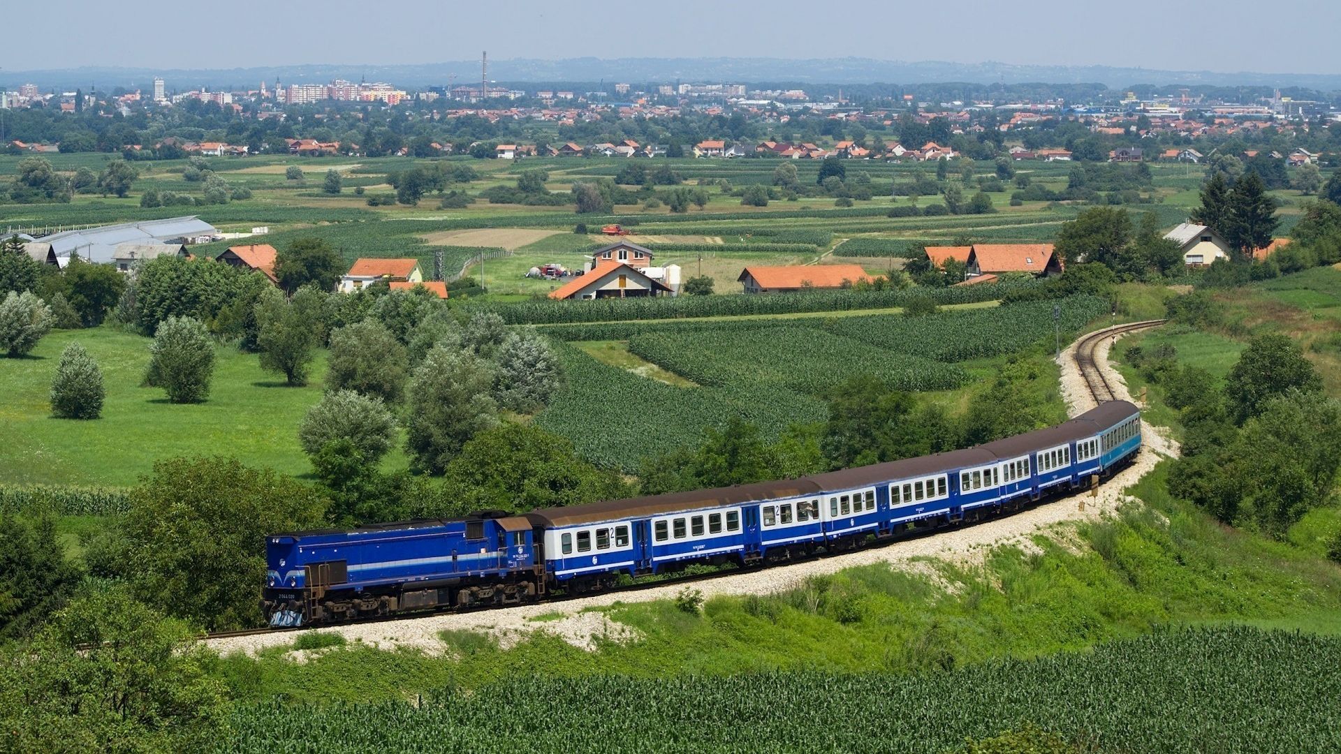 Download wallpaper 1920x1080 train, structure, dark blue, fields, trees, from above, city, suburb, distance, summer, railway full hd, hdtv, fhd, 1080p HD background
