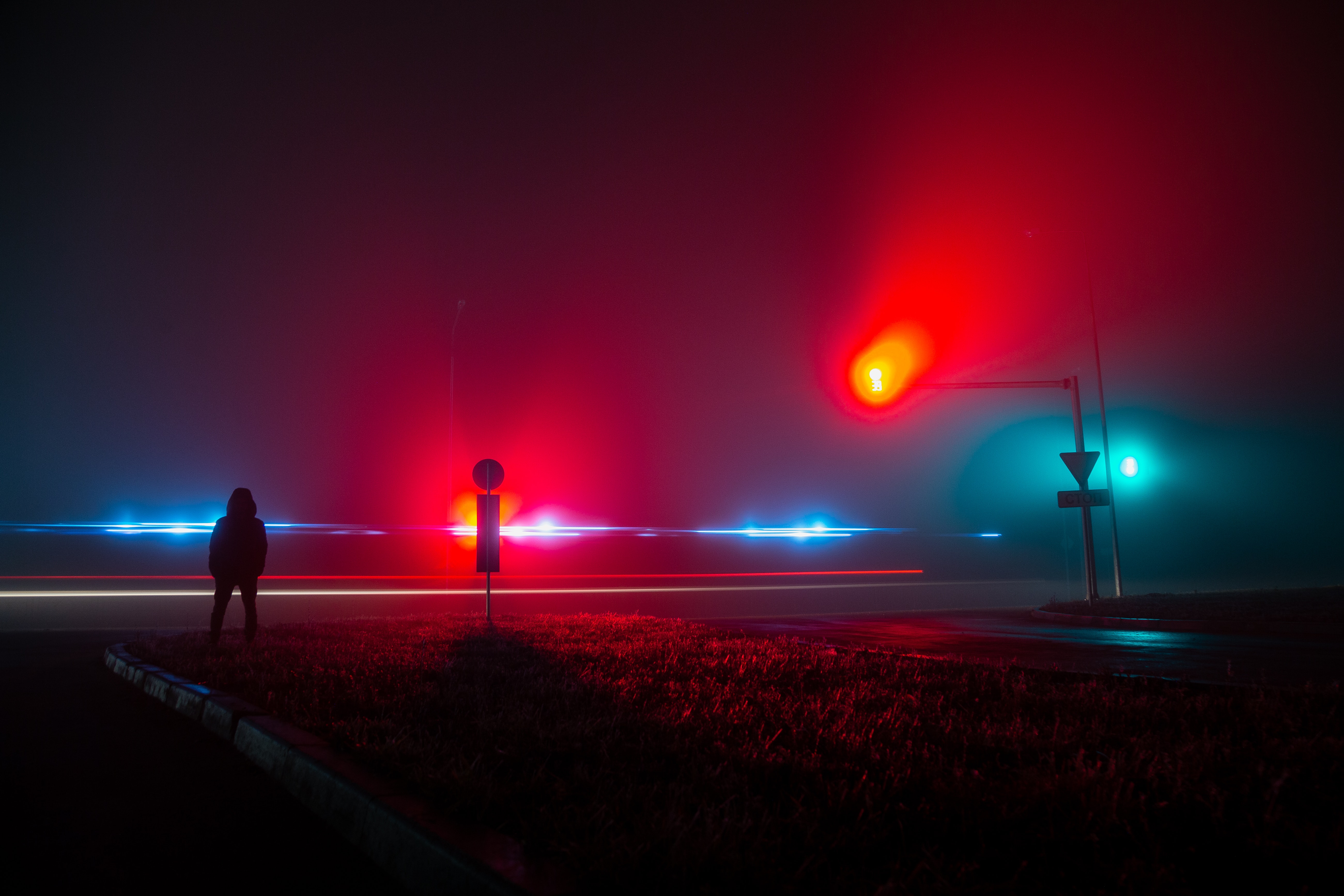 Unrecognizable Person Observing Red and Blue Lights on Road at Night · Free