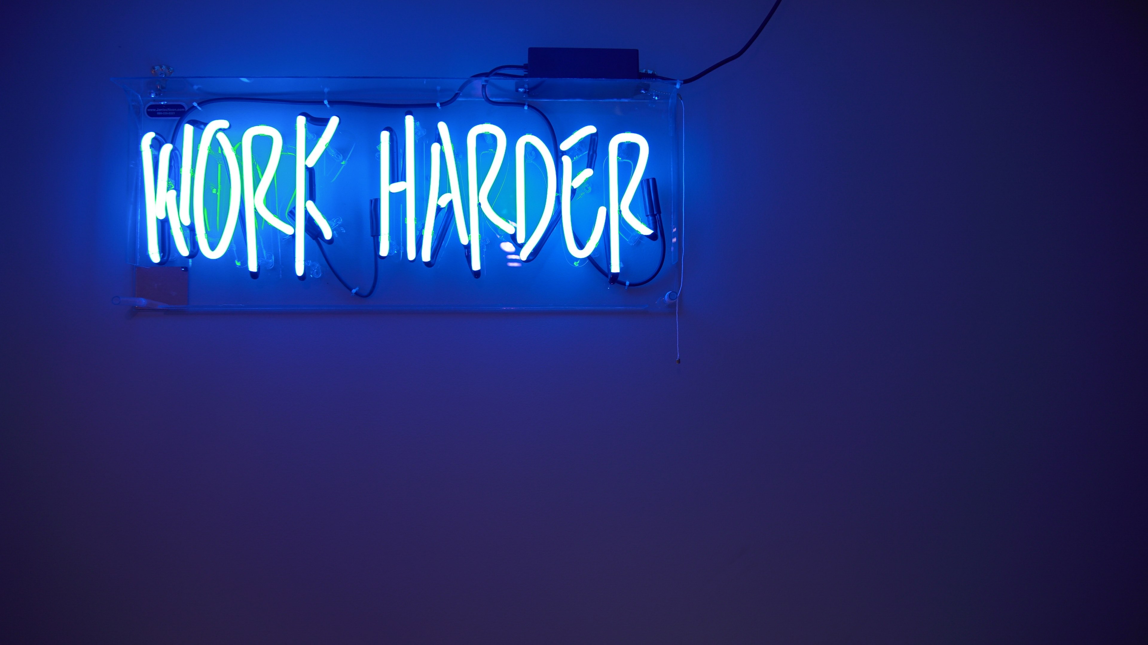 Wallpaper / a bright blue neon on a wall reads work harder, work harder neon 4k wallpaper free download